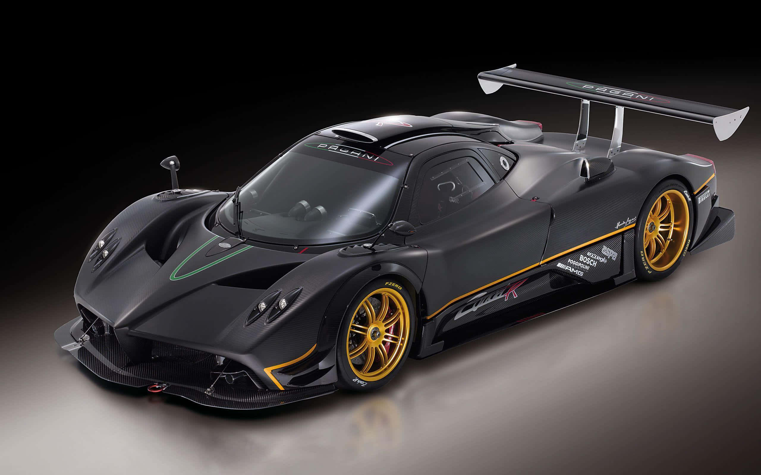 Pagani Zonda R 桌布 壁紙 — 一輛時尚的啞光黑色帕加尼Zonda R賽車，配備金色輪圈和空氣動力學尾翼，在攝影棚燈光下閃耀。