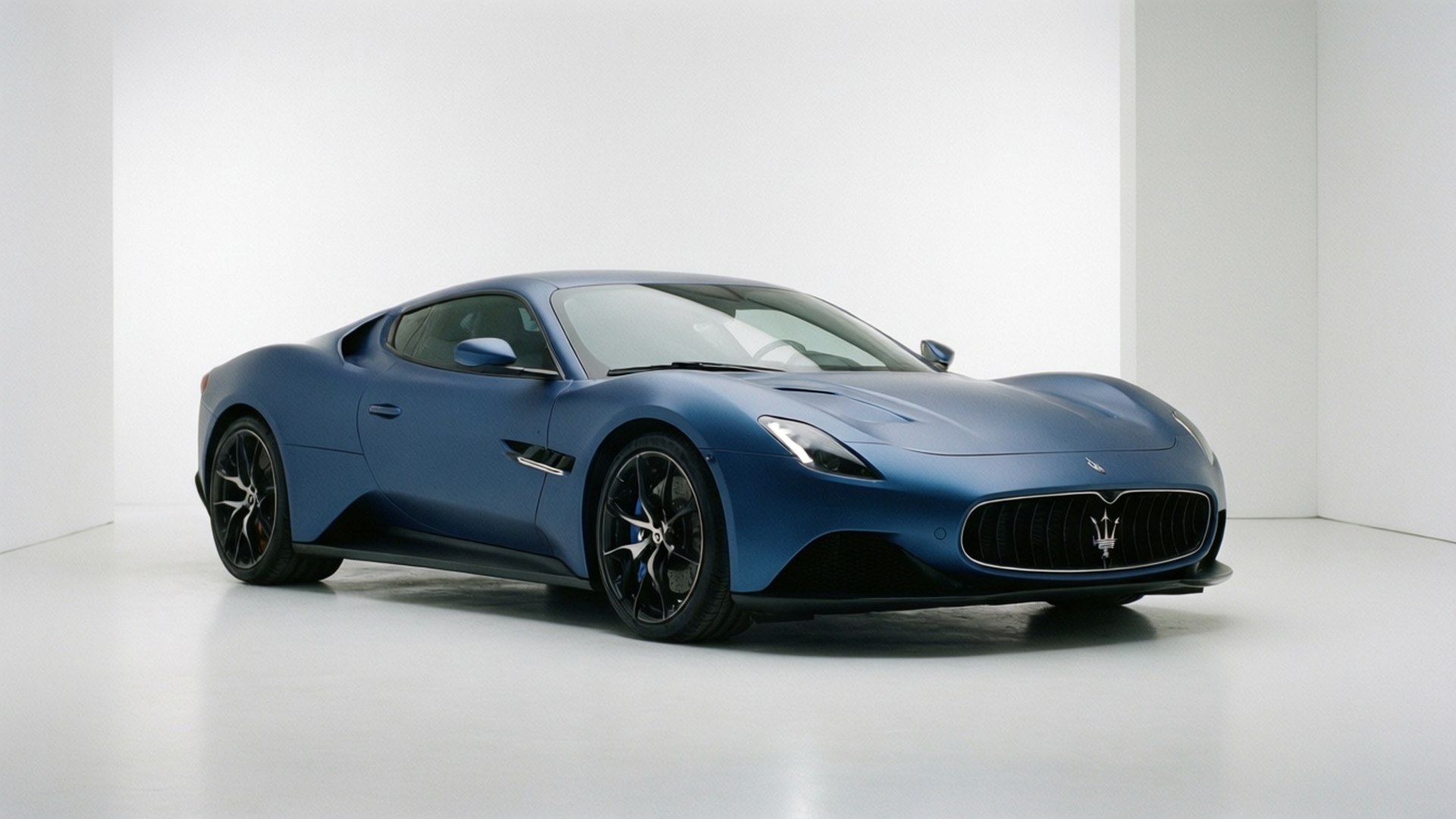 Maserati Shamal 桌布 壁紙 — 一架時尚的啞光藍色瑪莎拉蒂跑車在簡約的白色工作室中展示，配有柔和燈光。