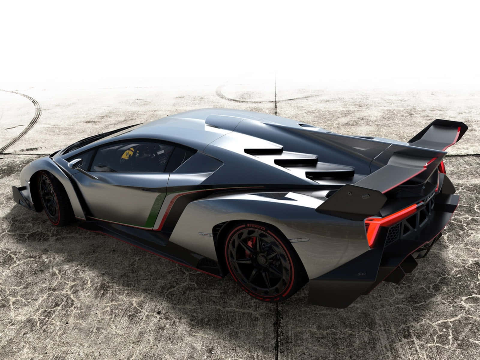 Lamborghini Veneno 桌布 壁紙 — 一架流線型銀色林寶堅尼Veneno帶有紅色點綴，停泊在裂開的混凝土上，展示其進取的氣動力設計及大型尾翼。