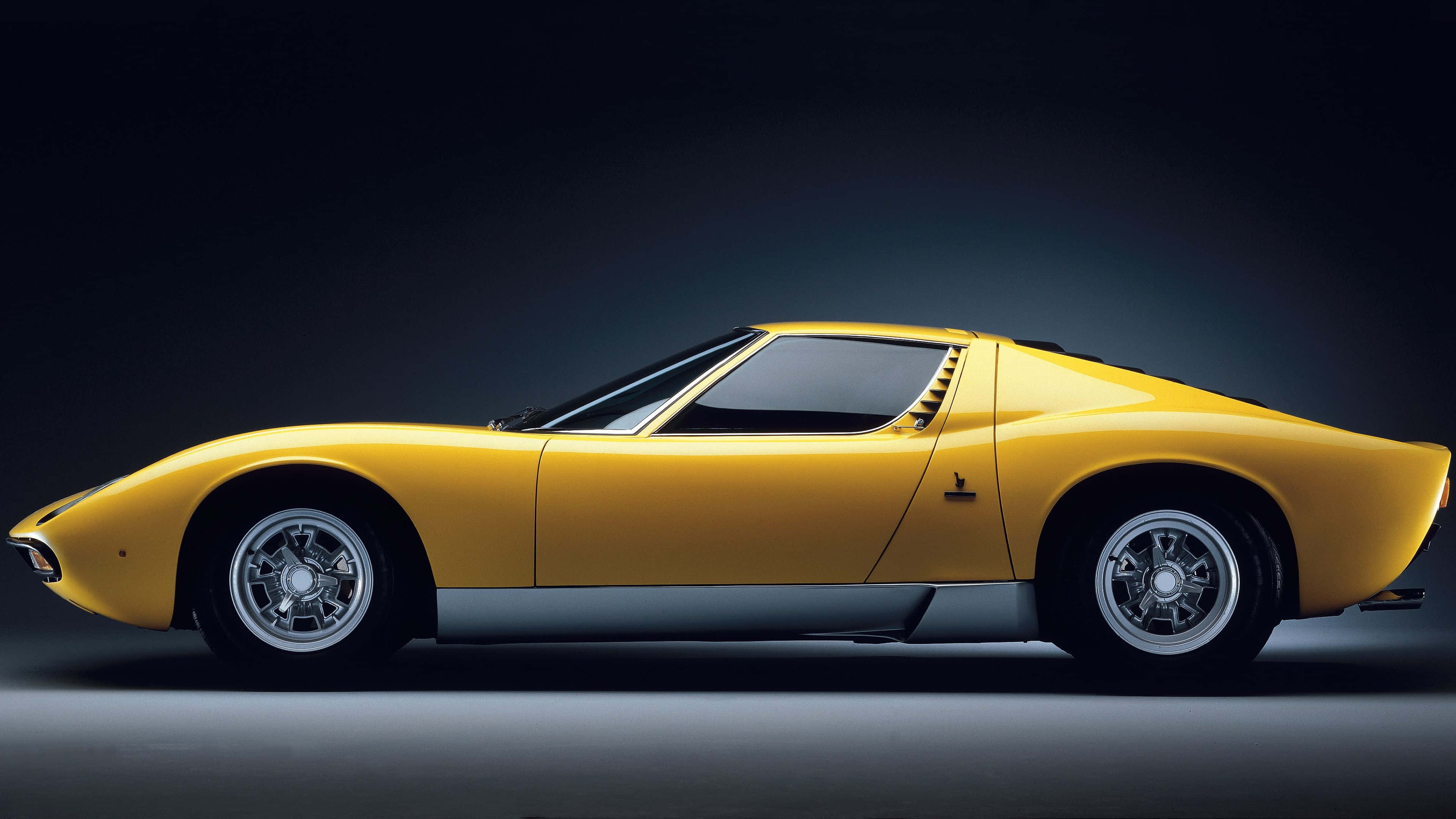 Lamborghini Miura 桌布 壁紙 — 一輛時尚的黃色林寶堅尼Miura跑車在暗色漸變背景下的攝影棚燈光中閃耀。