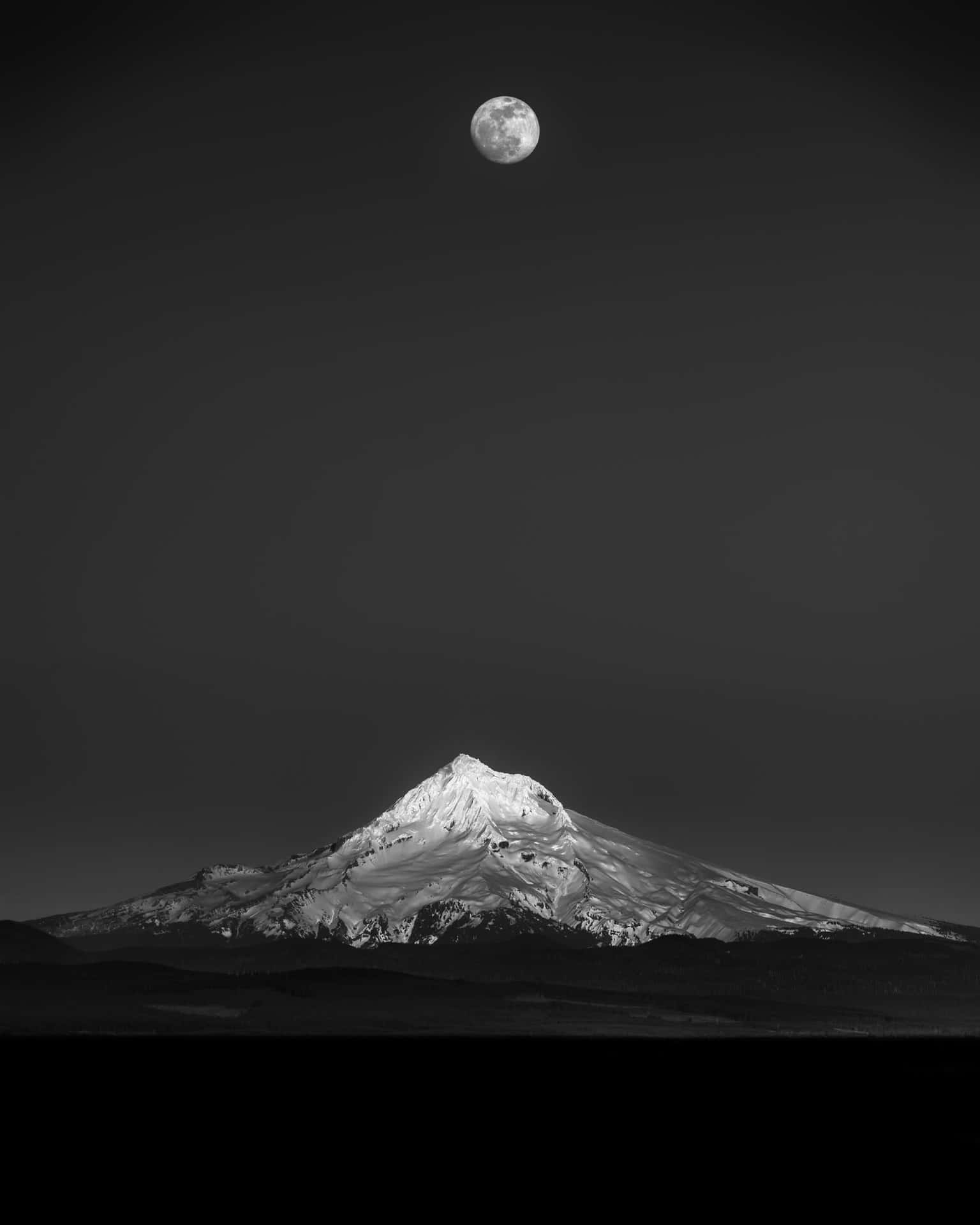 夜晚滿月下白雪覆蓋的山峰，黑白風格。