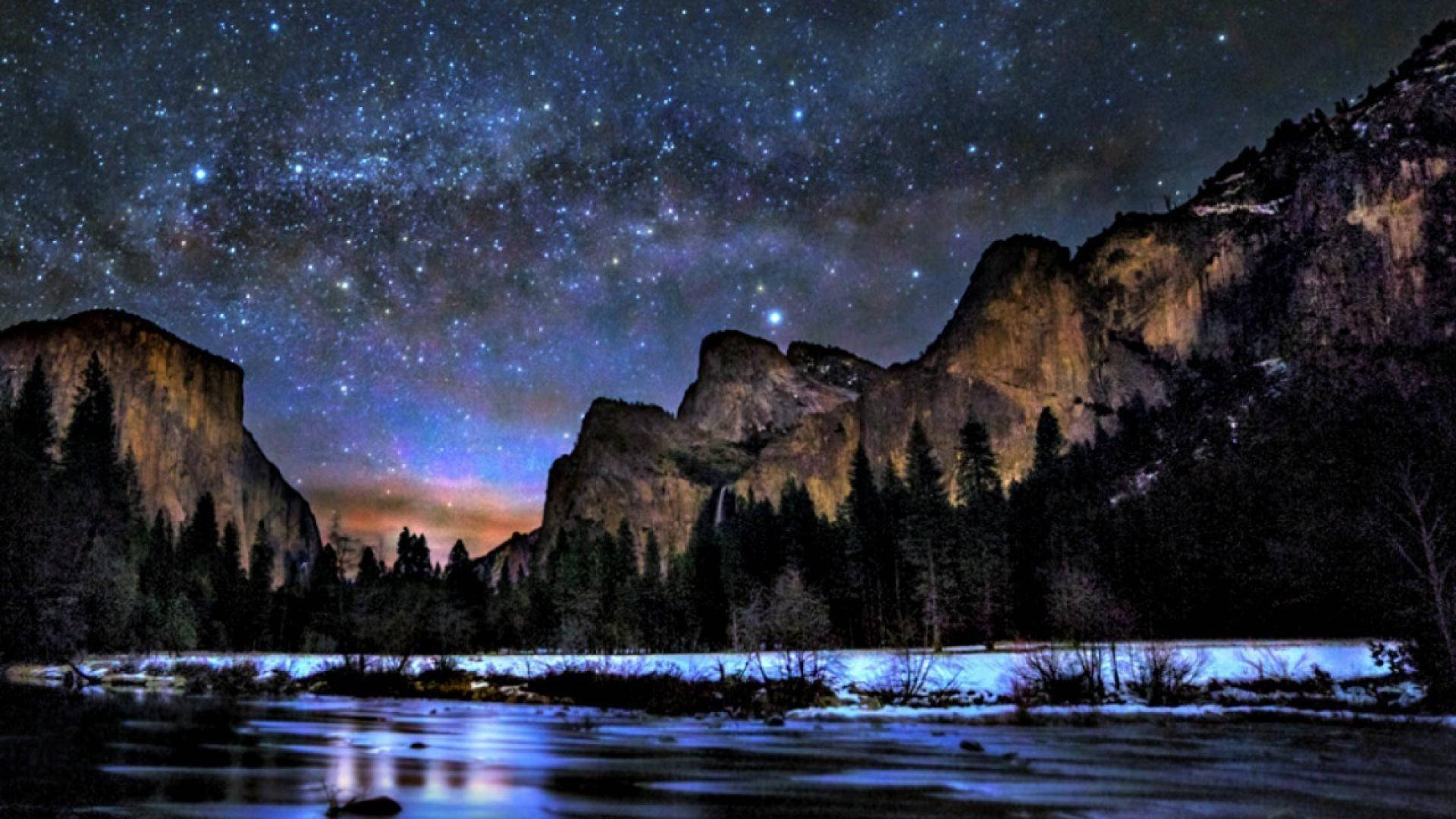 寧靜夜空繁星 壁紙 — 星空之夜在白雪覆蓋的山脈和發光的河流之上拱起，一片寧靜的荒野。