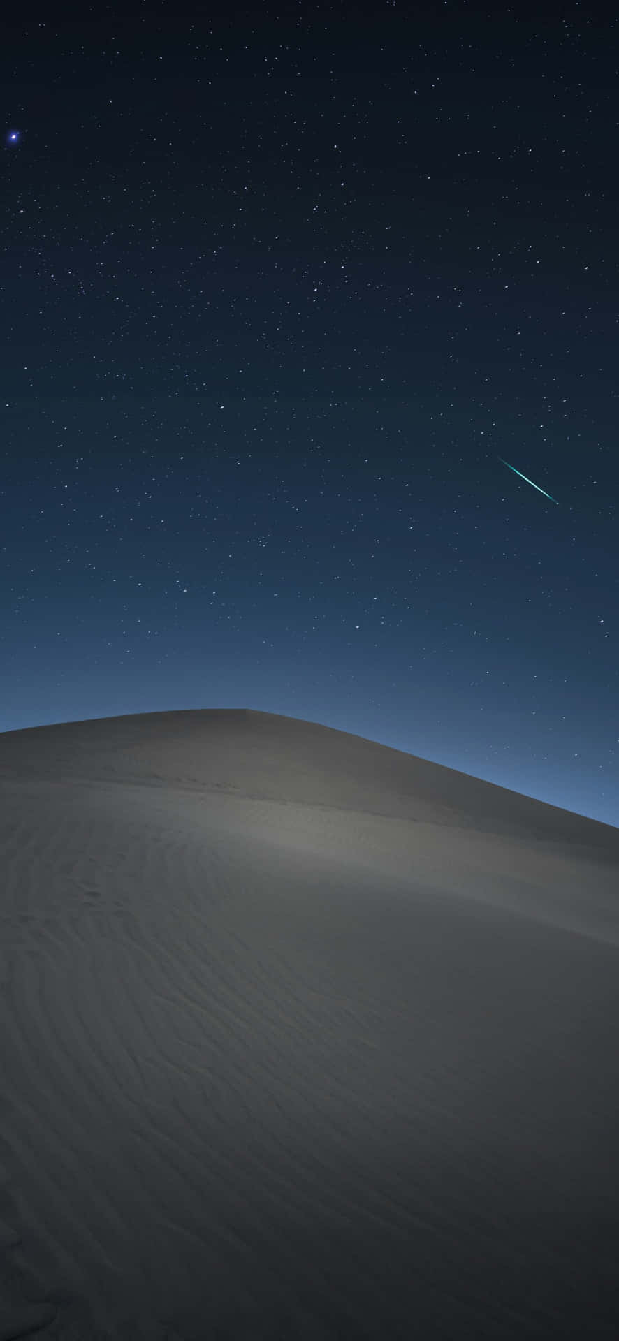  壁紙 — 在深藍色天空下，一顆發光的流星劃過廣闊沙漠沙丘上方的星空夜空。