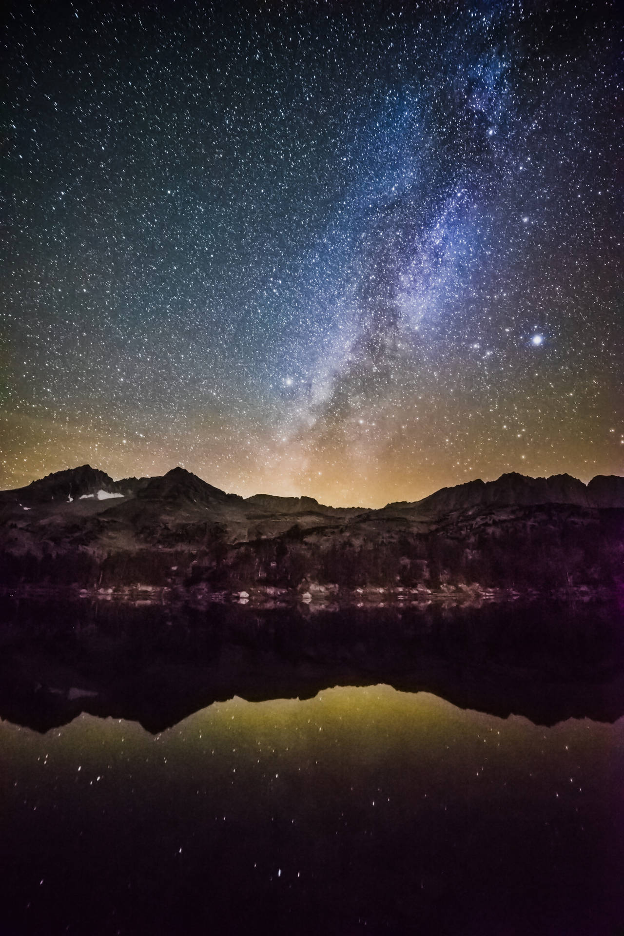在星空之夜下，銀河系倒映在山間湖泊中。