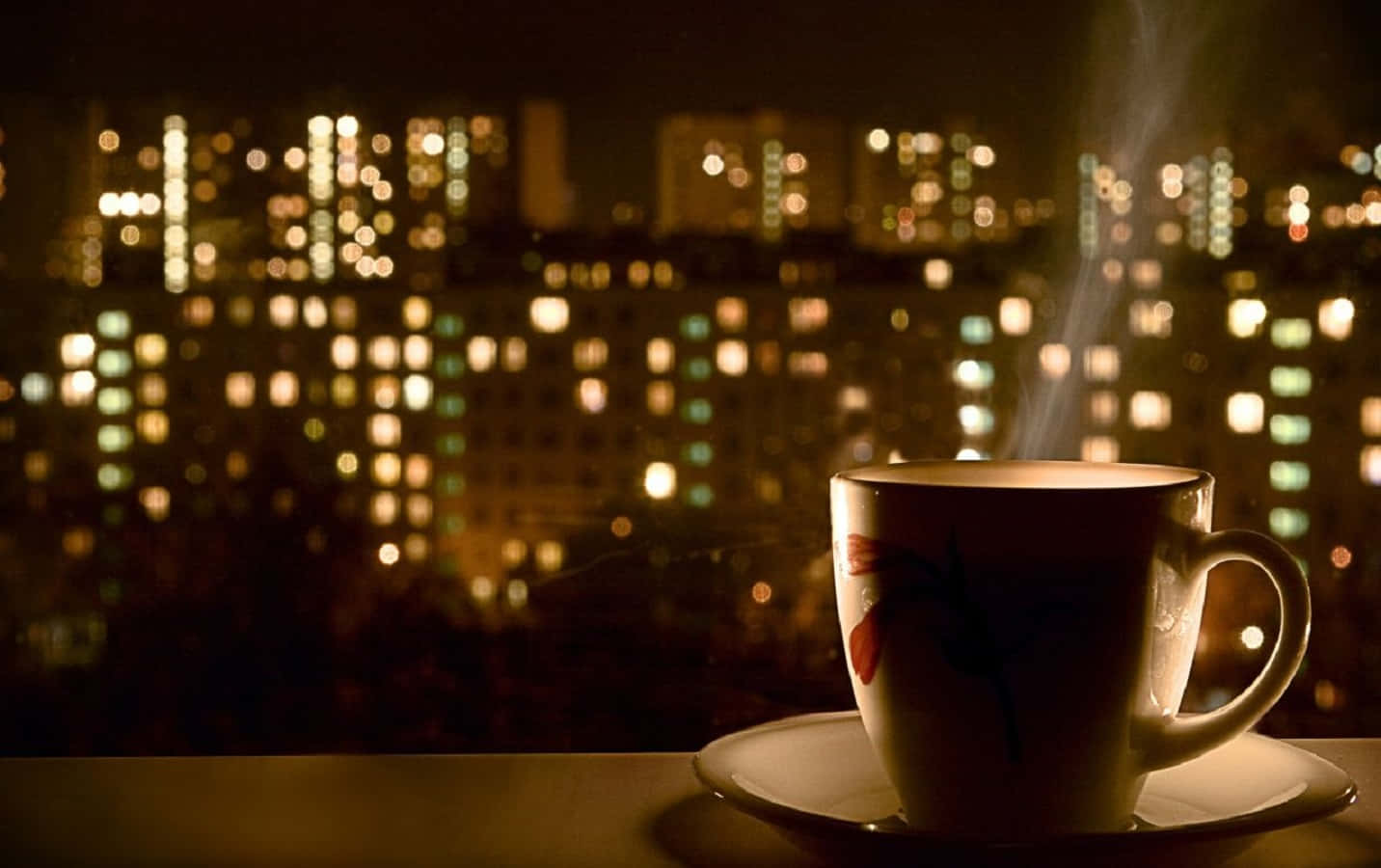 窗台上的一杯冒煙的茶，背景是模糊的城市夜景。