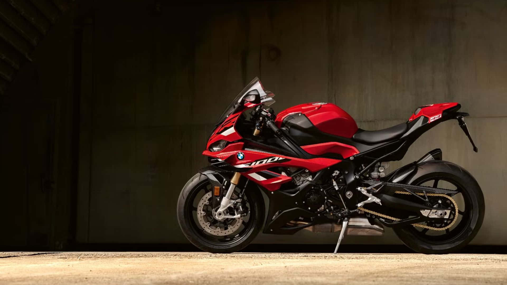  壁紙 — 一架搶眼的紅黑色BMW S1000RR電單車，在燈光昏暗的混凝土車庫中，以戲劇性的燈光呈現。
