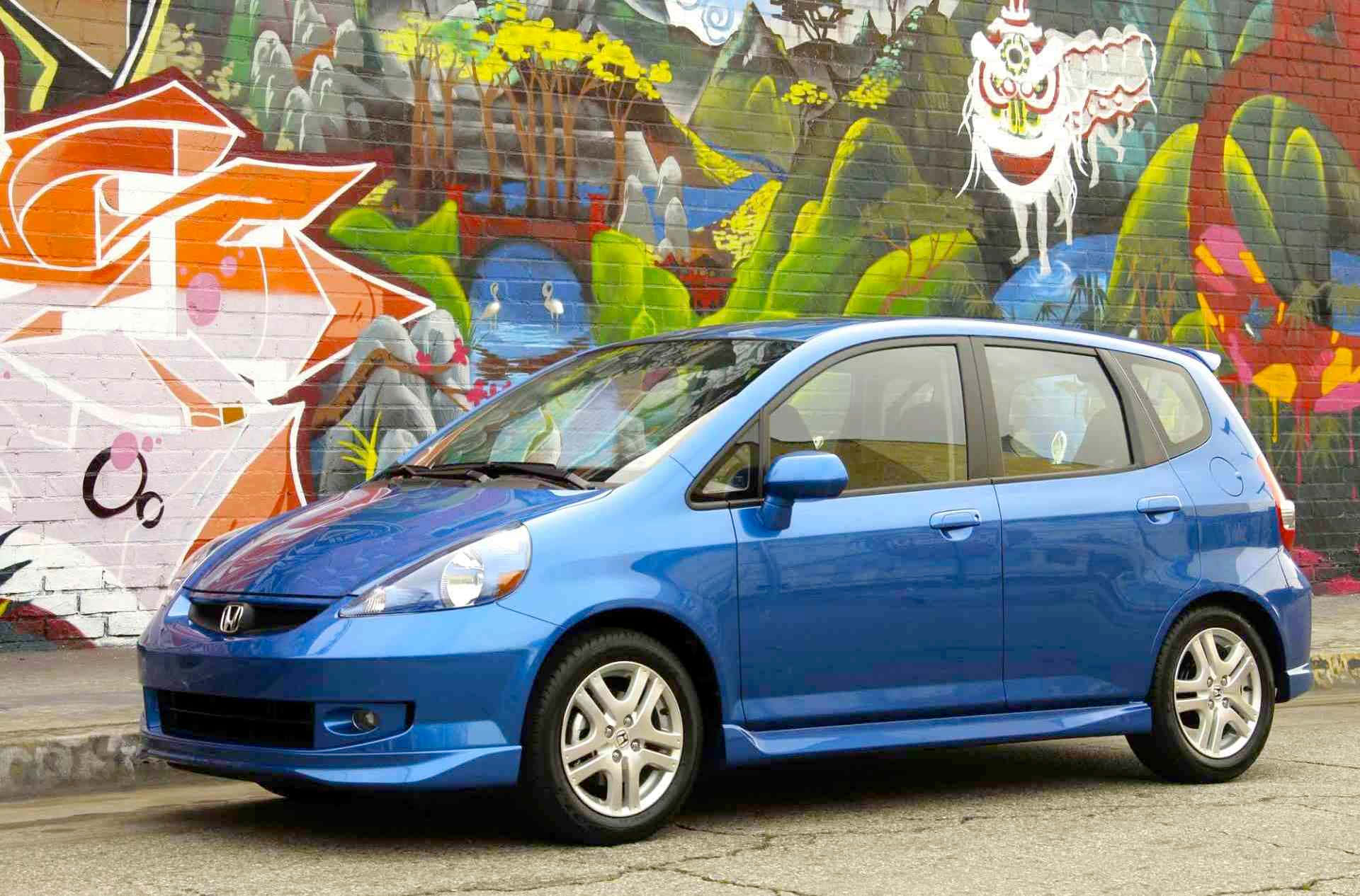 Honda Fit 桌布 壁紙 — 一架充滿活力的藍色本田Fit停在一幅色彩繽紛、佈滿塗鴉的牆前，牆上有卡通風格的山脈和動物壁畫。