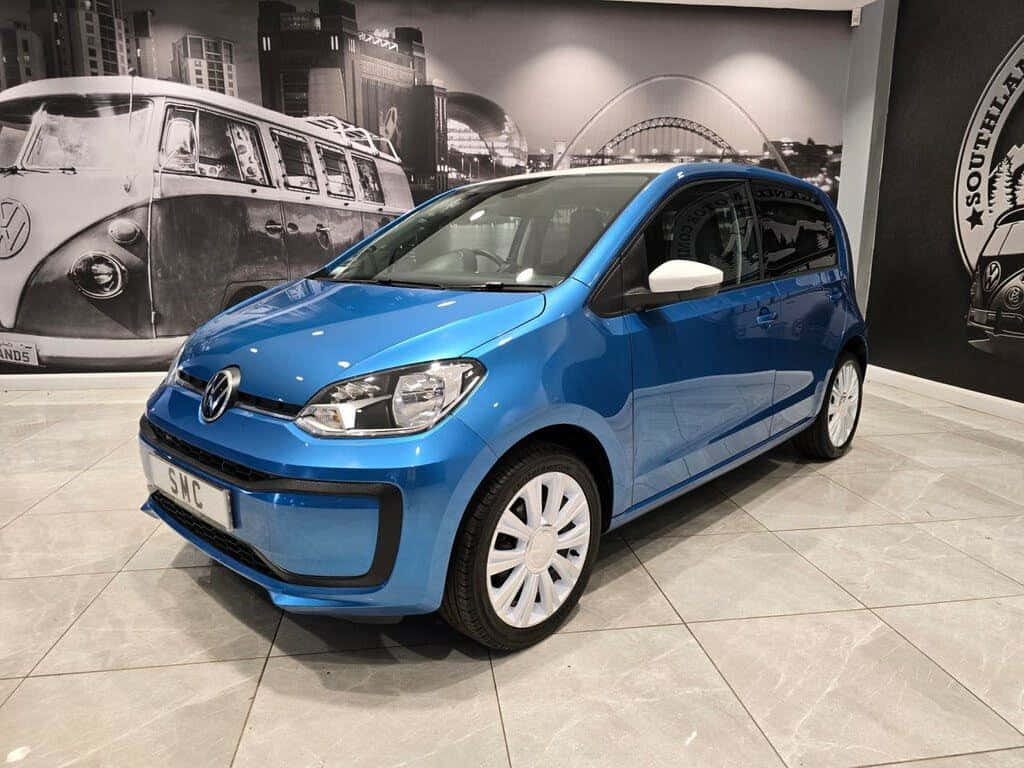  壁紙 — 一輛充滿活力的藍色Volkswagen up!在時尚的陳列室中展示，地板鋪有瓷磚，牆上掛有復古VW壁畫。