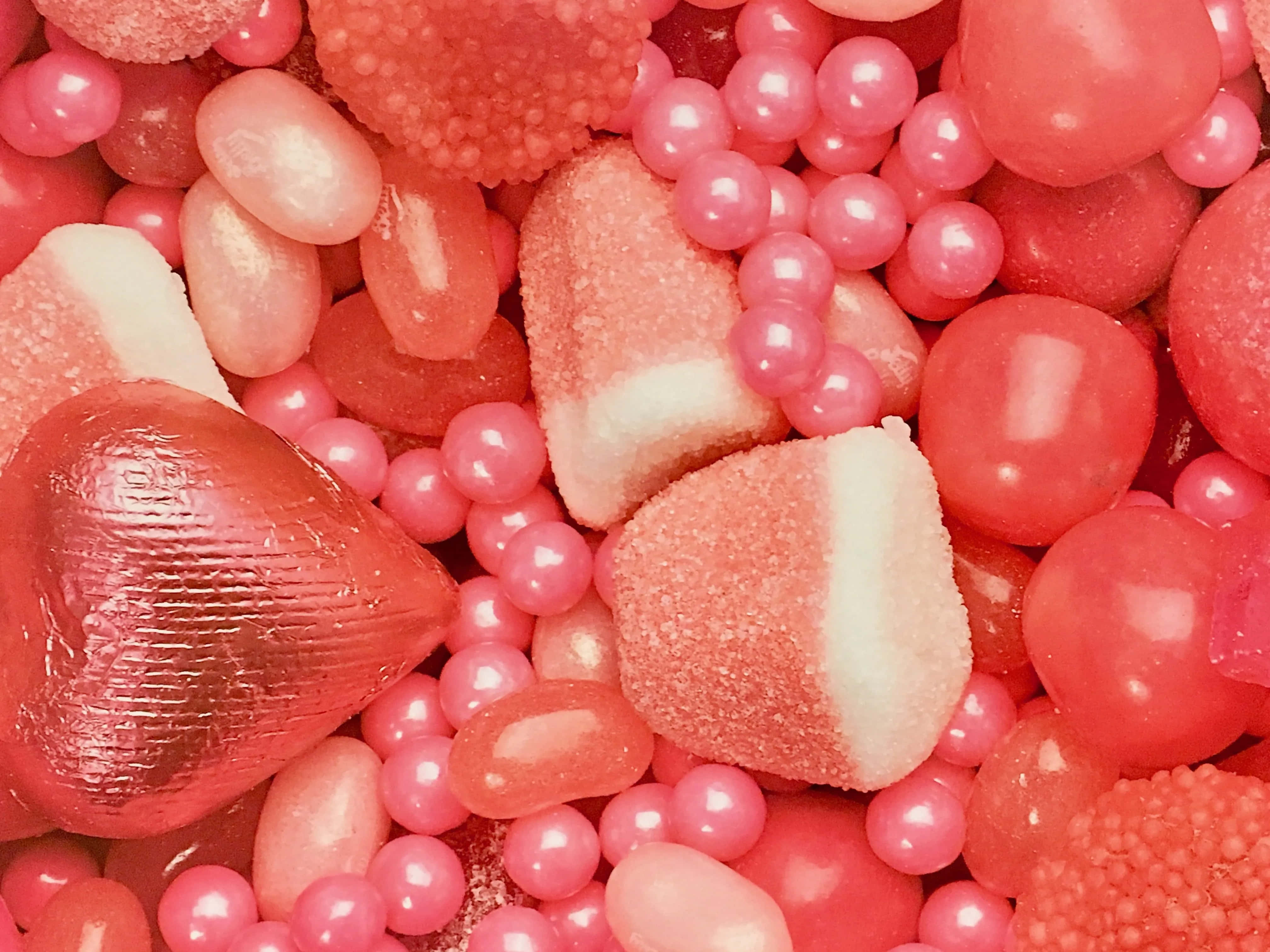 Pink Candy 桌布 壁紙 — 各種粉紅色糖果（包括心形朱古力和糖衣球體）的鮮豔特寫。