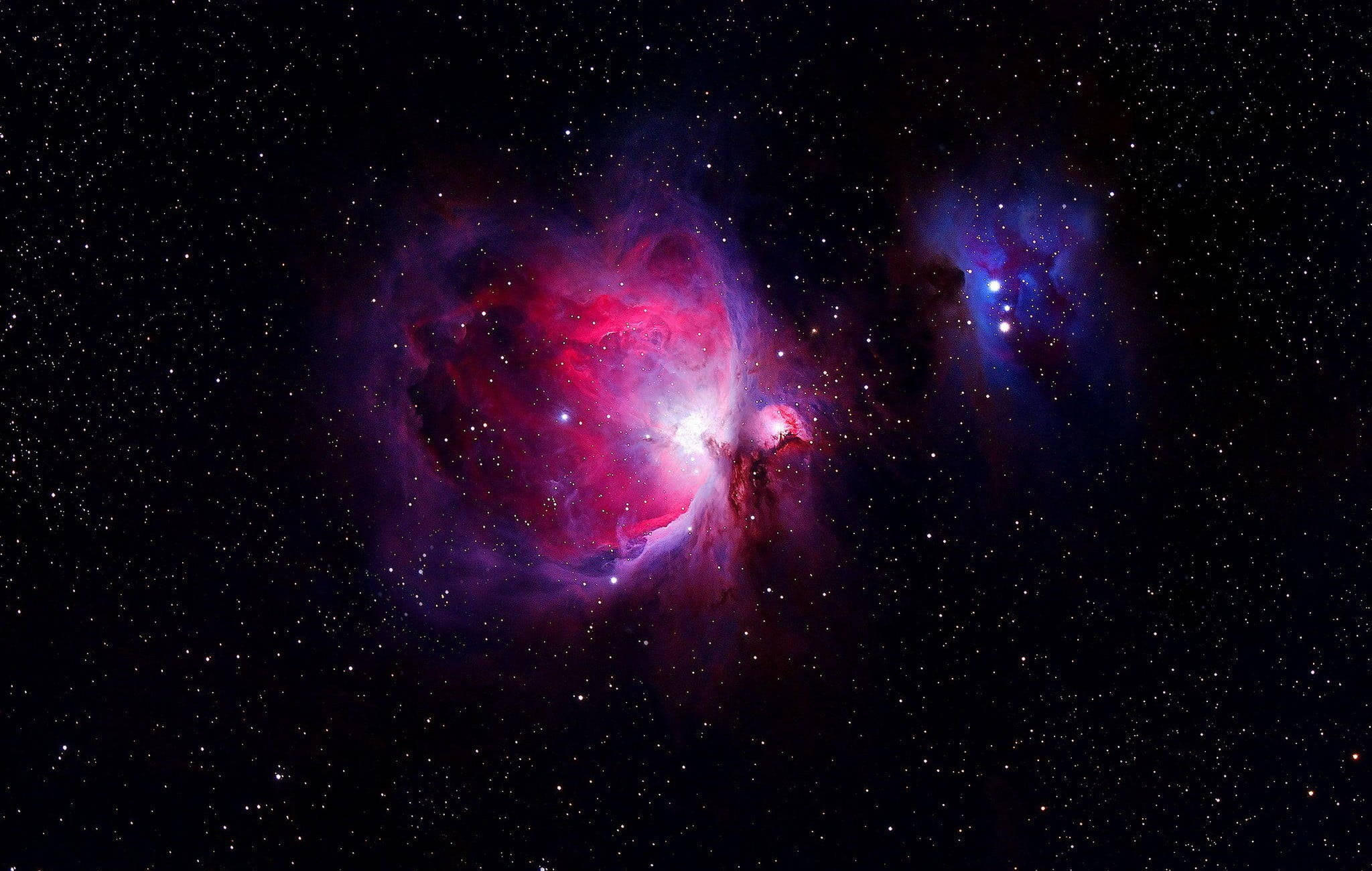 銀河 桌布 壁紙 — 一個充滿活力的宇宙星雲在佈滿星星的黑色虛空中散發出粉紅色和紫色的光芒。