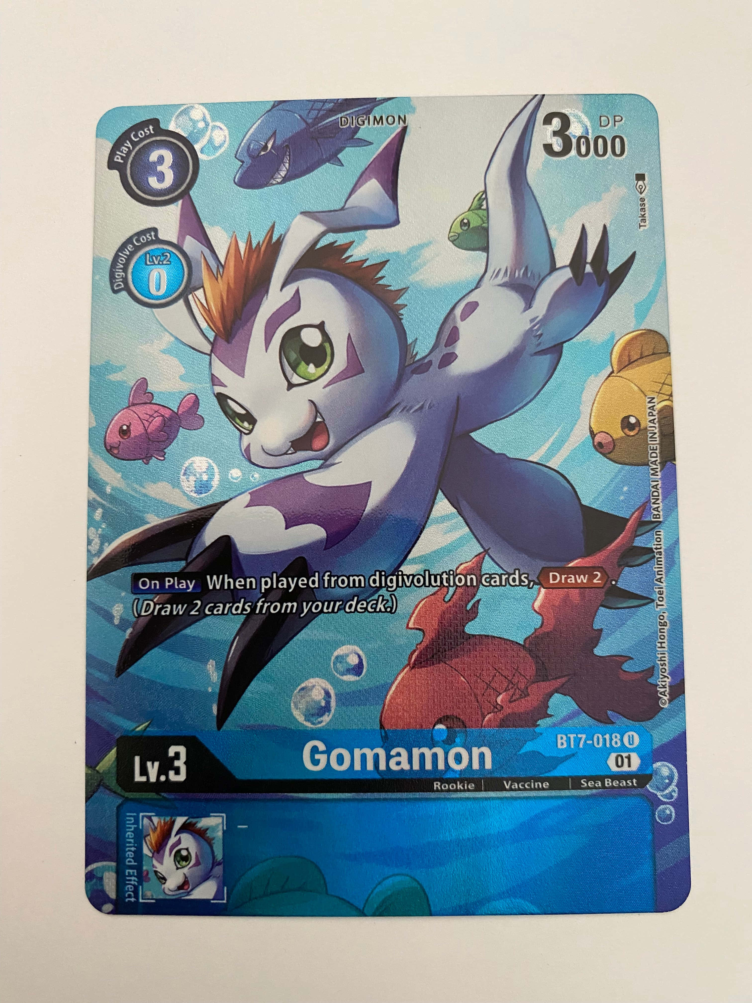 Digimon Gomamon 桌布 壁紙 — 一張充滿活力的數碼暴龍集換式卡牌，描繪哥瑪獸在水下與色彩繽紛的魚和氣泡一起游泳。