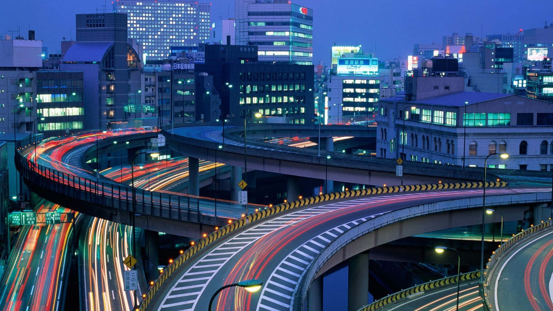 夜晚的城市，發光的建築物和高架道路上的車燈條紋。