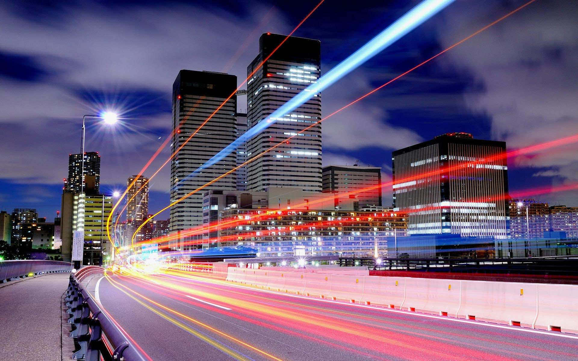 夜晚的城市高速公路，光跡和高樓大廈在黑暗的天空下。