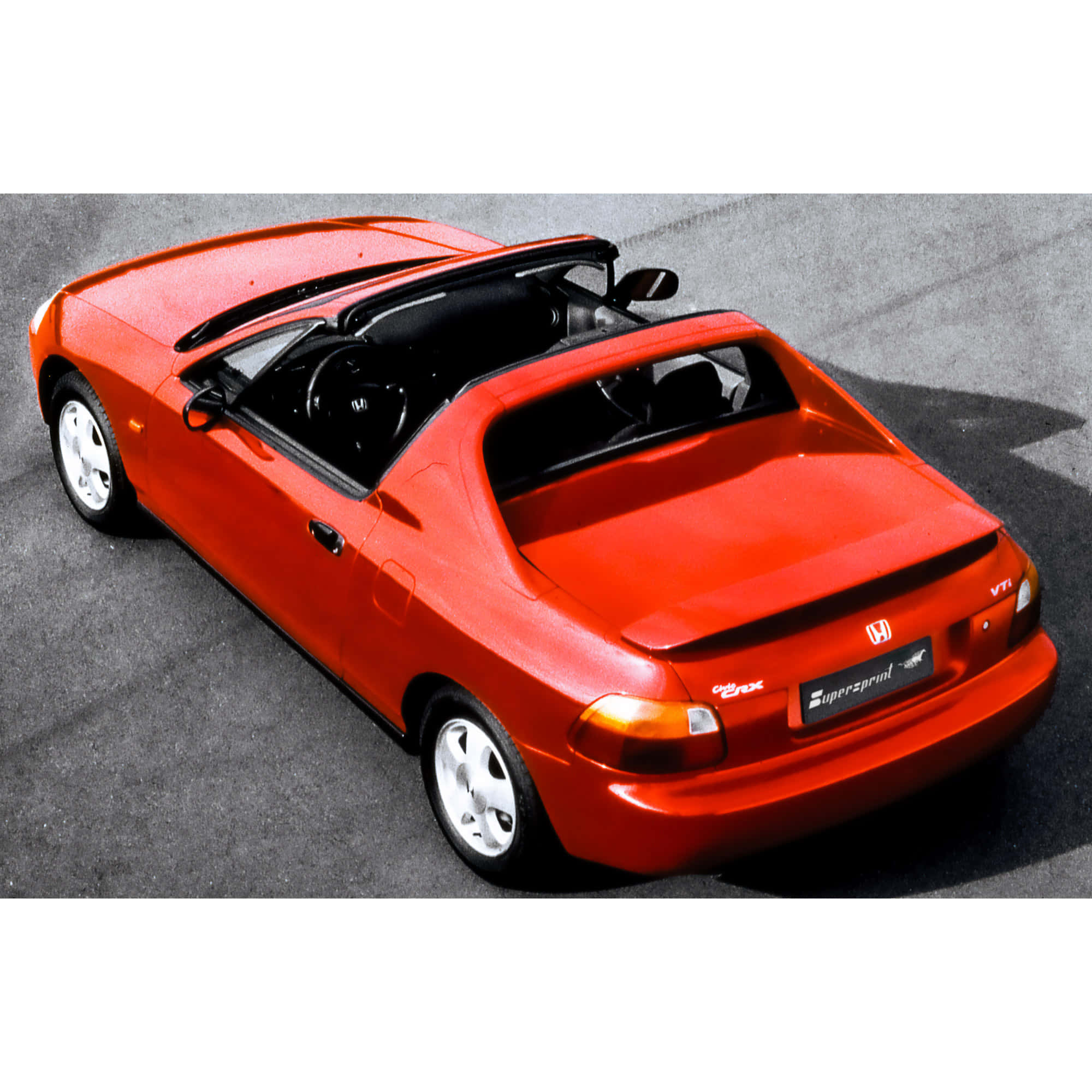 Honda Civic Del Sol 桌布 壁紙 — 一輛鮮紅色的本田S2000開篷跑車在明亮的日光下停泊在灰色瀝青路上。