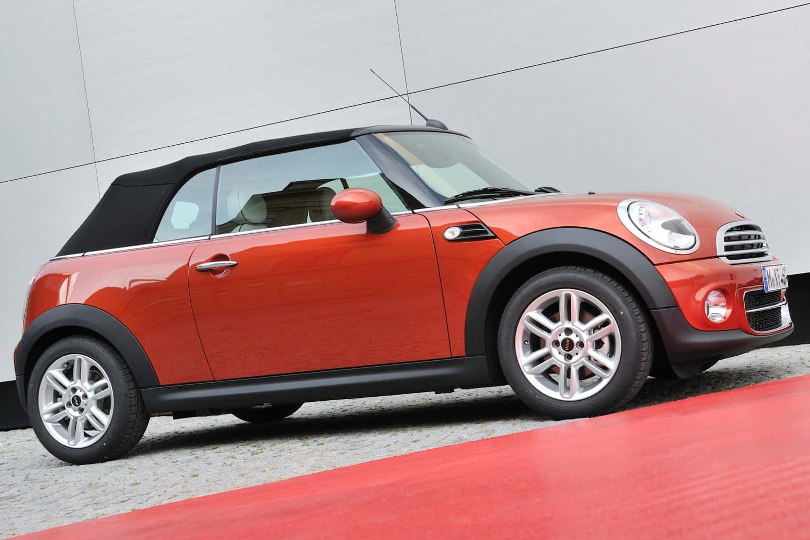 Mini Cooper Convertible 桌布 壁紙 — 一輛鮮紅色的MINI Cooper開篷車停在紅色地毯上，背景是簡約的灰色牆壁。
