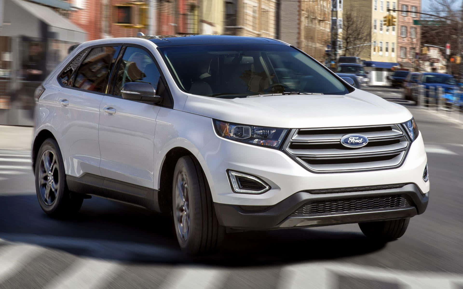 Ford Edge 桌布 壁紙 — 一輛白色福特Edge SUV在城市街道上行駛，車輪和背景建築物帶有動態模糊效果。