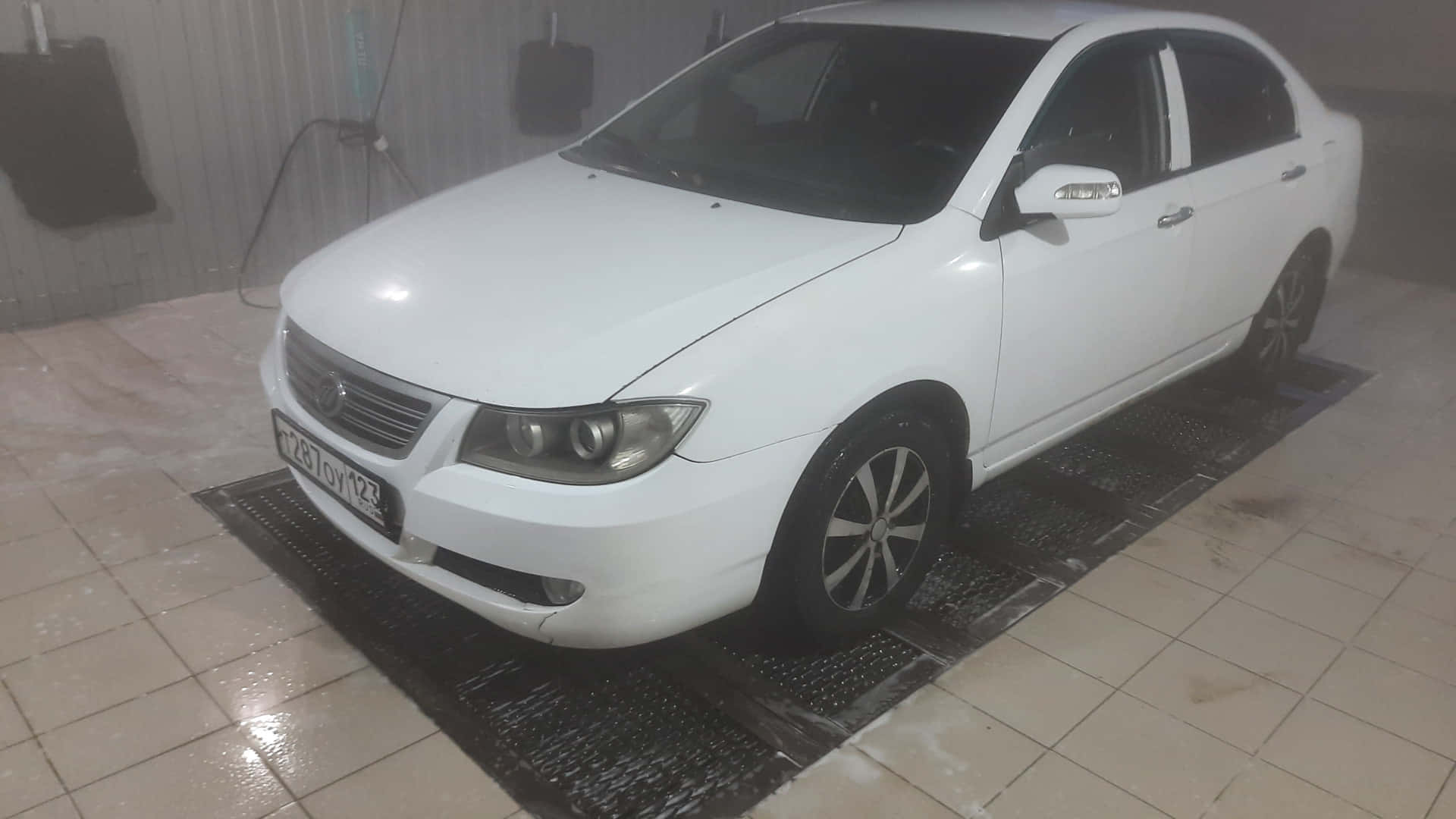 Lifan 620 桌布 壁紙 — 一輛白色房車正在室內洗車場的濕格柵上被清洗，周圍有蒸汽升起。