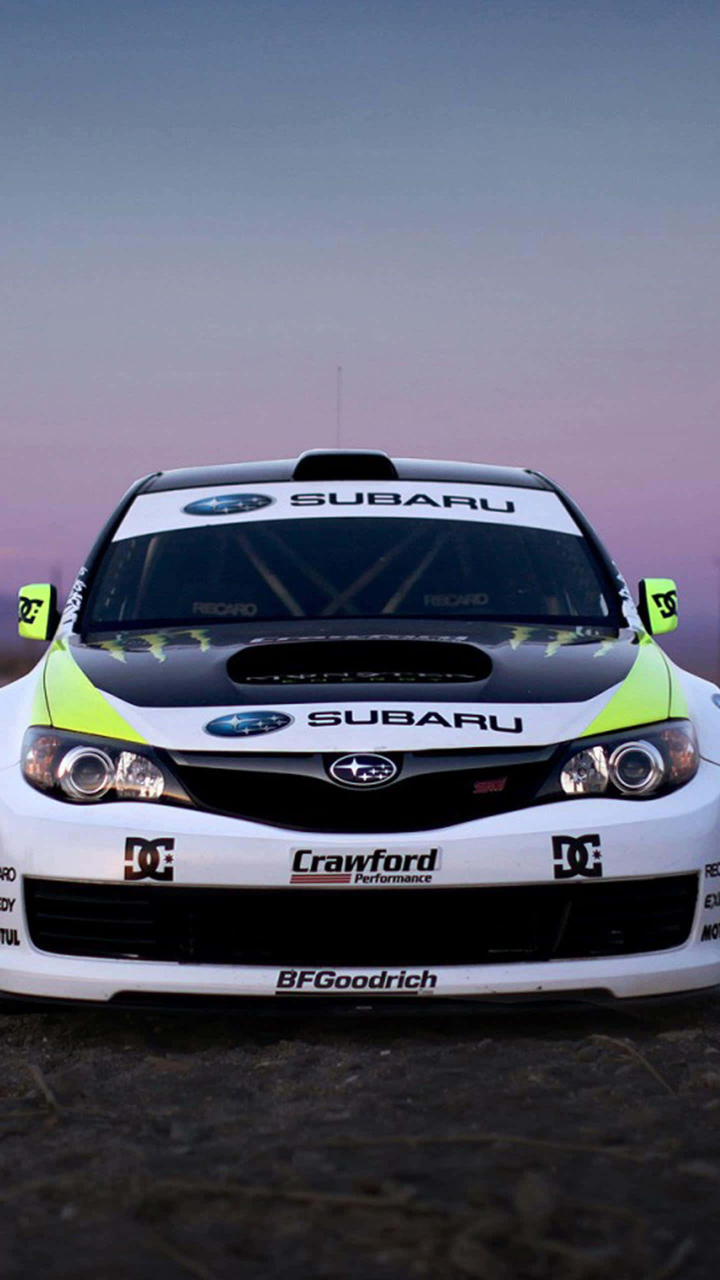 Ken Block 桌布 壁紙 — 一架白色Subaru拉力賽車帶有螢光綠色點綴，在紫色暮色天空下的岩石表面上正面朝前。