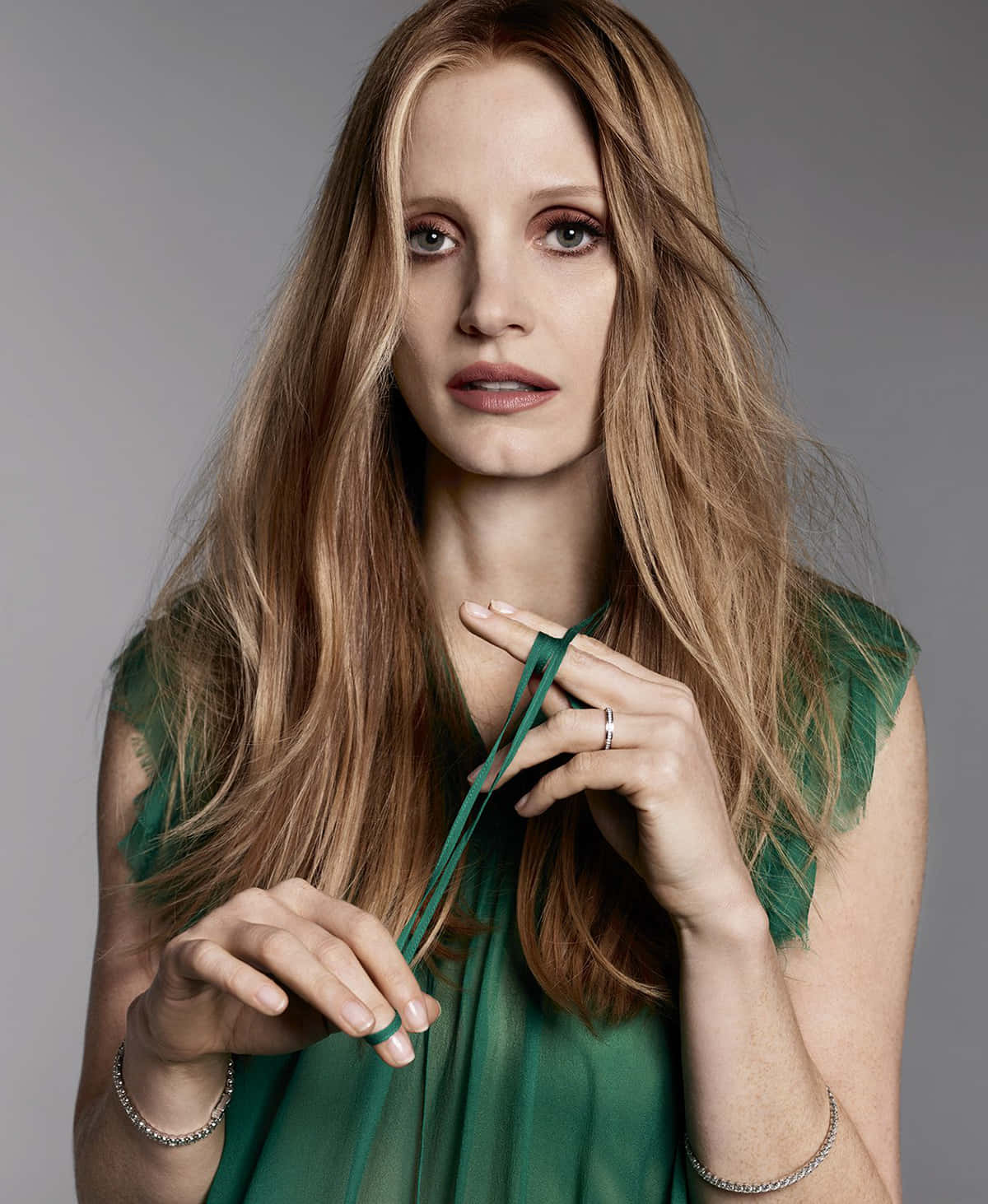 jessica chastain 桌布 壁紙 — 一位長金髮女性穿著綠色連衣裙，在灰色背景前手持綠色絲帶。