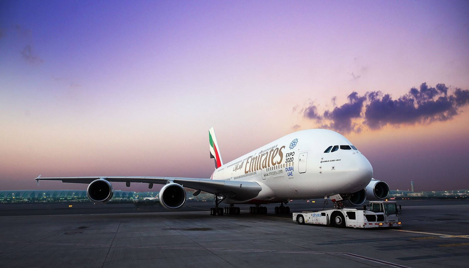 阿聯酋航空A380於多倫多國際機場 壁紙 — 一架巨大的阿聯酋航空空中巴士A380正在黃昏時分被拖過停機坪，上空是充滿活力的紫色和橙色天空。