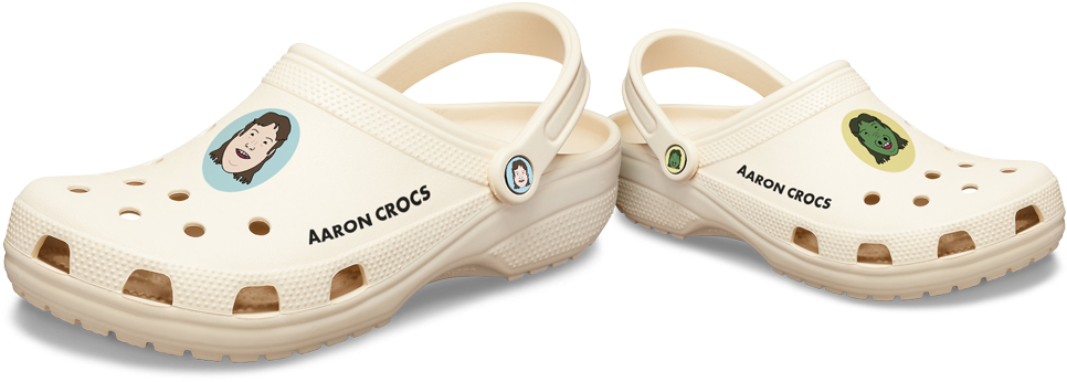 個人化Aaron Crocs鞋履 壁紙 — 兩雙奶油色Crocs木屐，帶有卡通角色貼片和「Aaron Crocs」文字，背景為黑色。