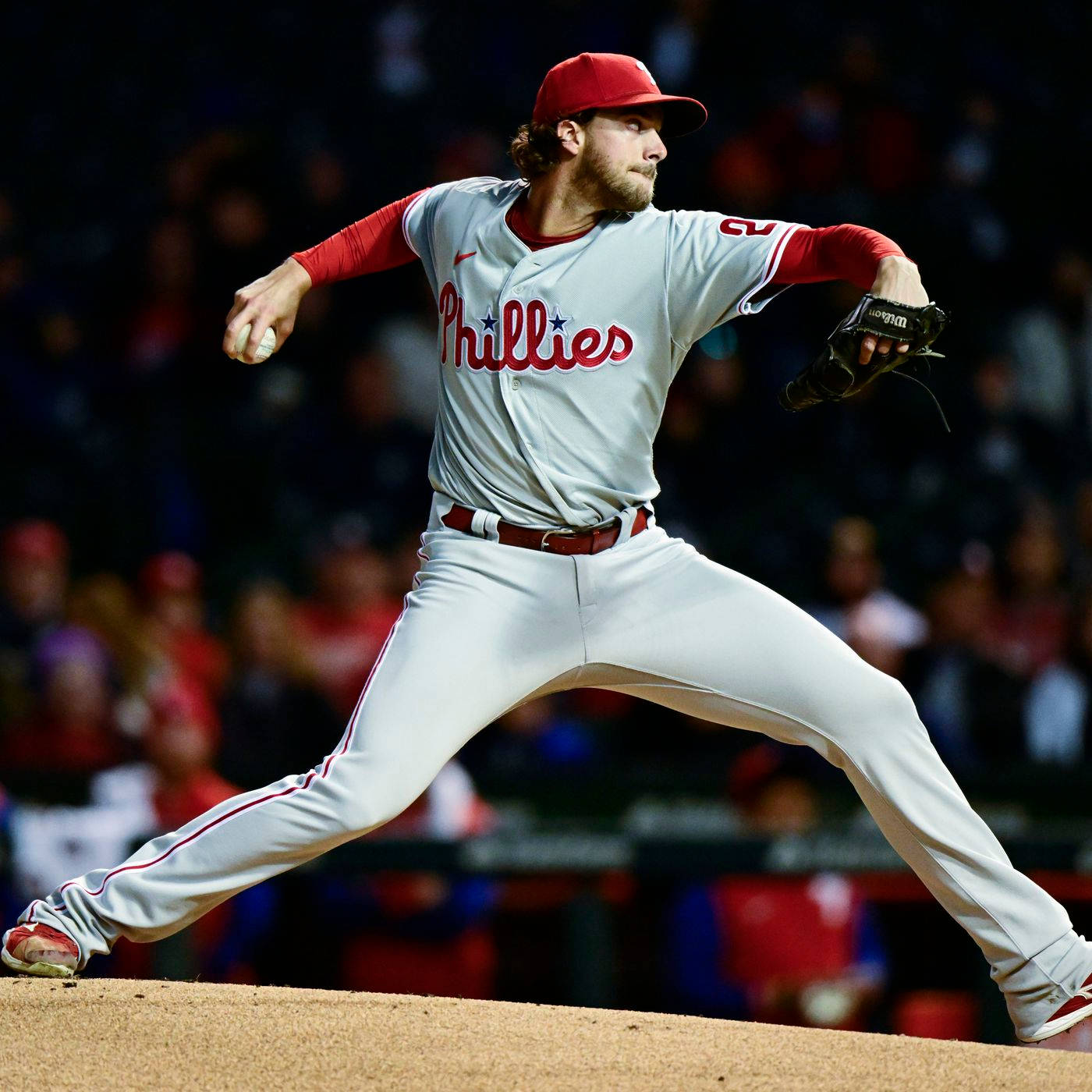 Aaron Nola 投球中 壁紙 — 費城費城人隊投手在球場燈光下於投手丘上投球，背景有模糊的球迷。