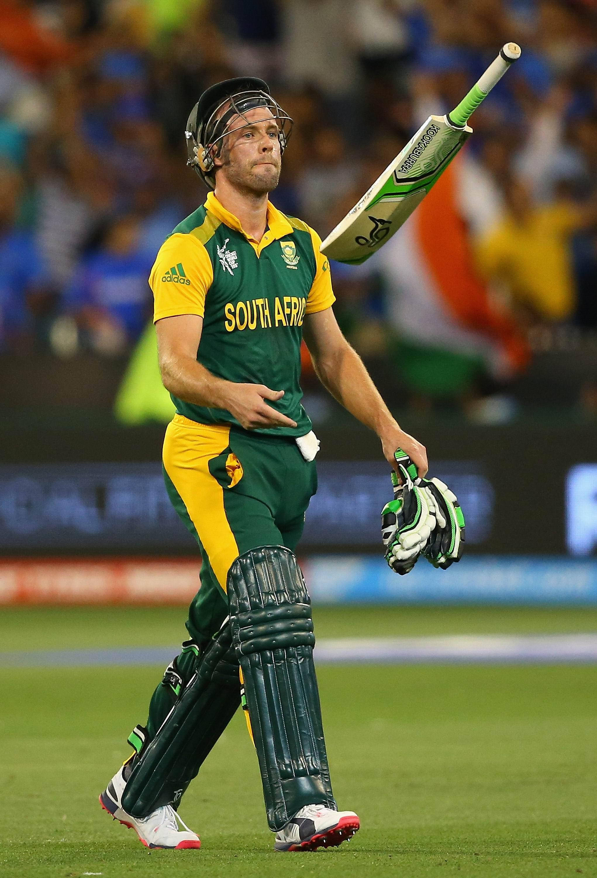 AB de Villiers 拿球棒玩耍 壁紙 — 一名身穿綠色和黃色球衣的南非板球運動員在球場燈光下拿著球棒和手套離開球場。