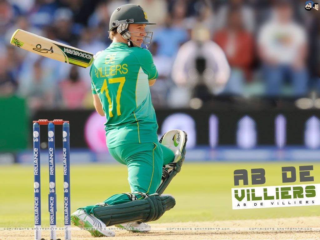 AB de Villiers 擊球時的精彩瞬間 壁紙 — 板球運動員 AB de Villiers 身穿綠色球衣，在陽光明媚的日間比賽中於草地上揮桿。
