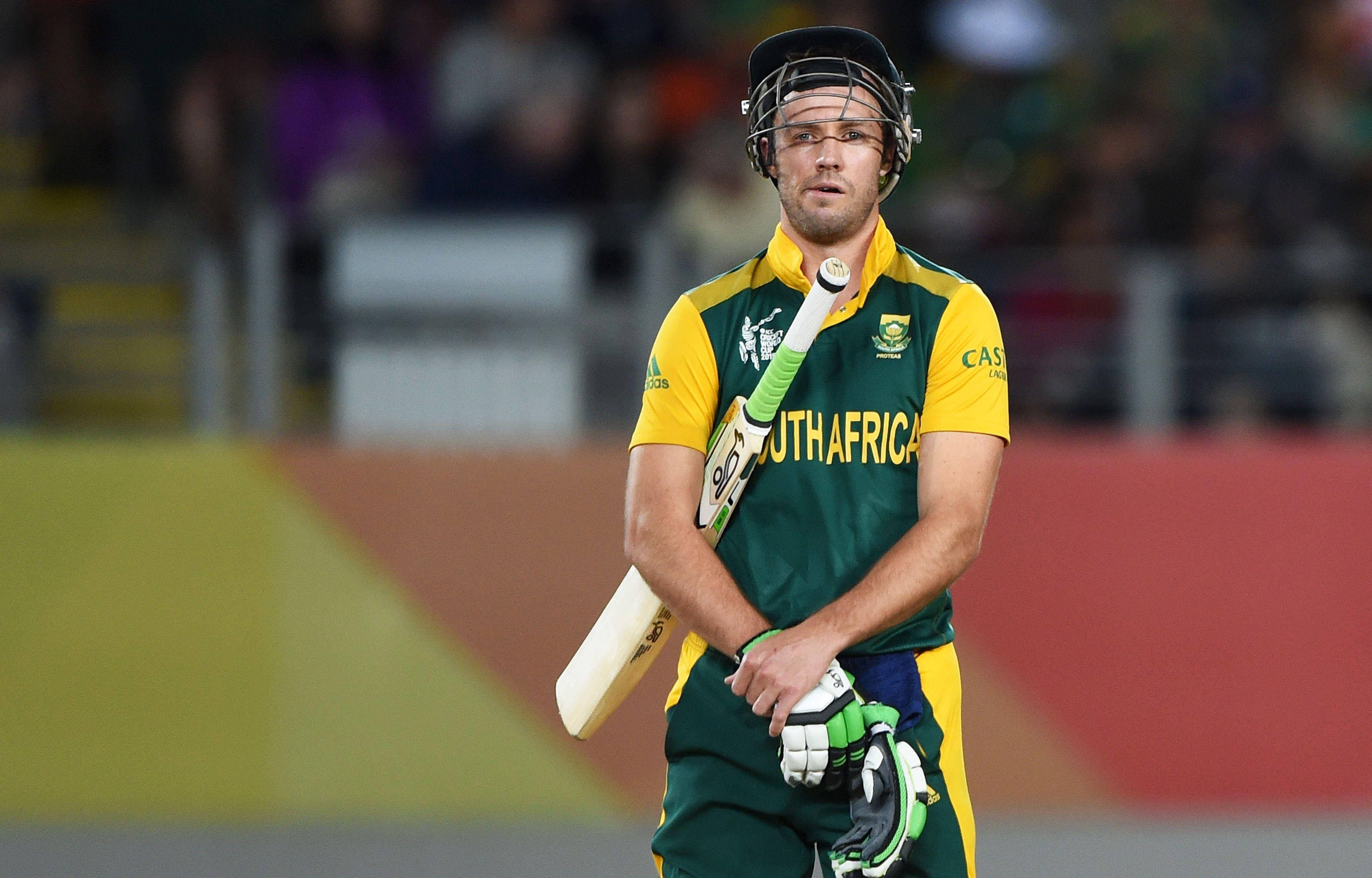 AB de Villiers 看起來無聊 壁紙 — 一位南非板球運動員身穿綠色和黃色制服，在體育場燈光下專注地握著球棒。