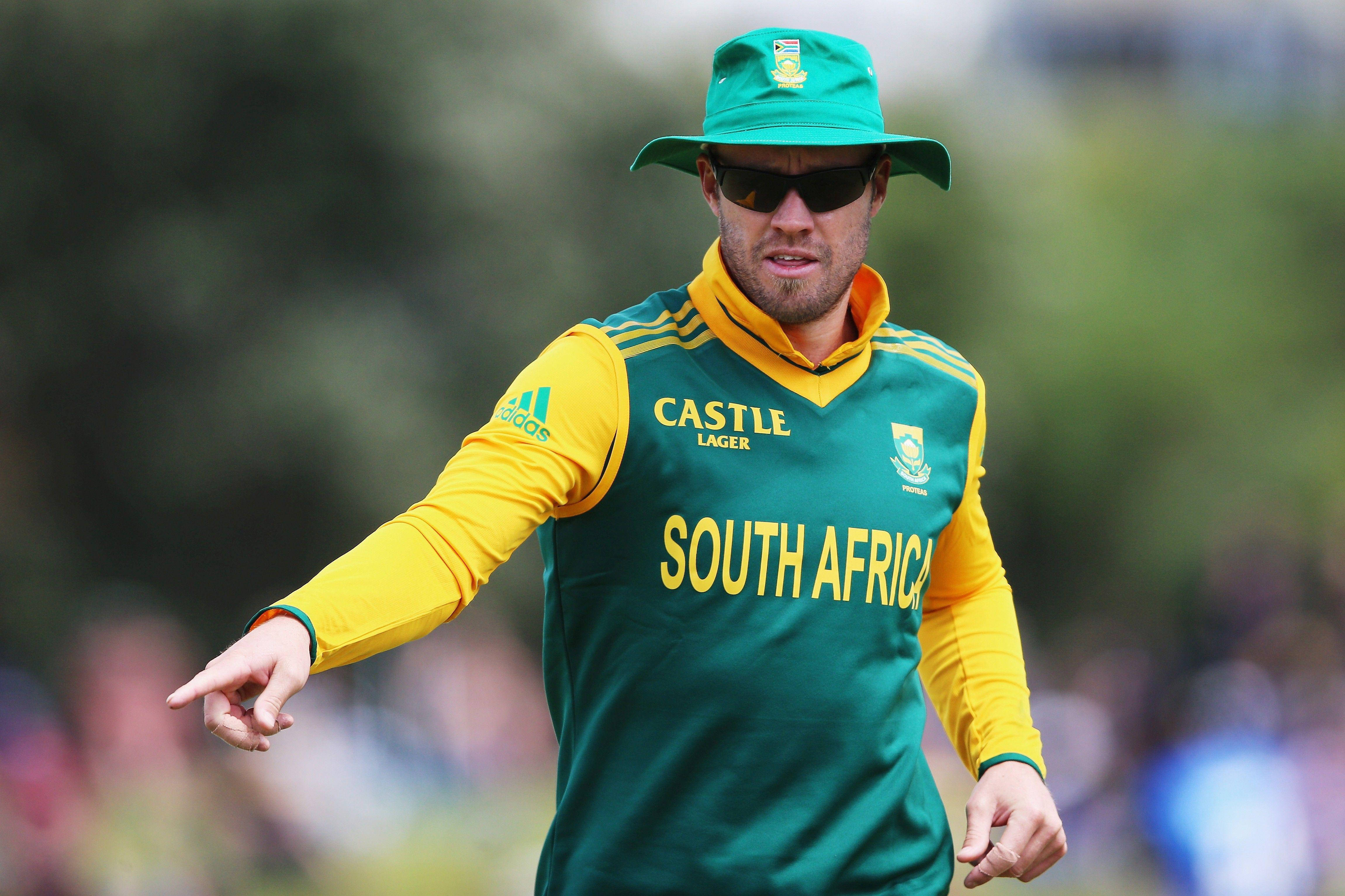 AB de Villiers 身穿球衣慢跑 壁紙 — 一名身穿綠色和黃色球衣的南非板球運動員在日間比賽中果斷地指向某處。