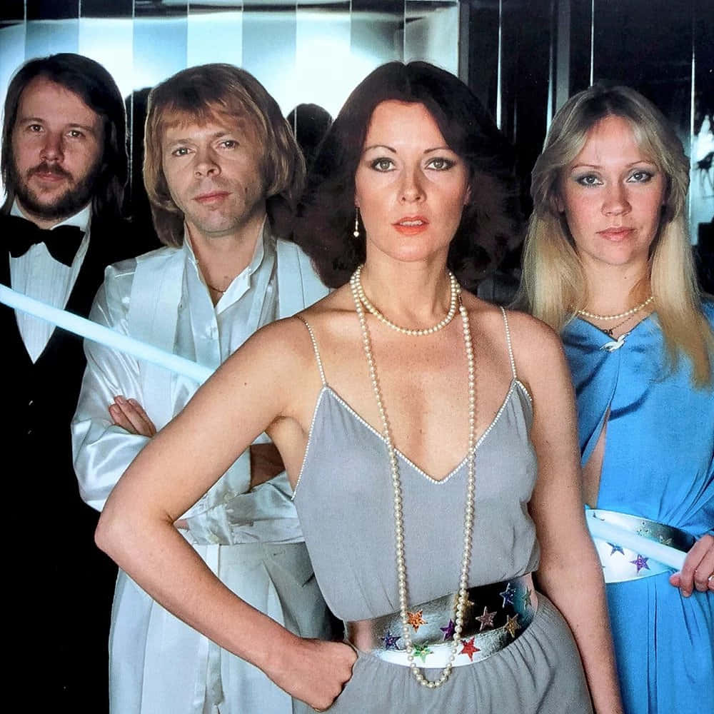 慶祝瑞典傳奇流行樂團ABBA 壁紙 — 四位華麗的1970年代音樂家穿著緞子和珍珠，在鏡面背景前自信地擺姿勢。