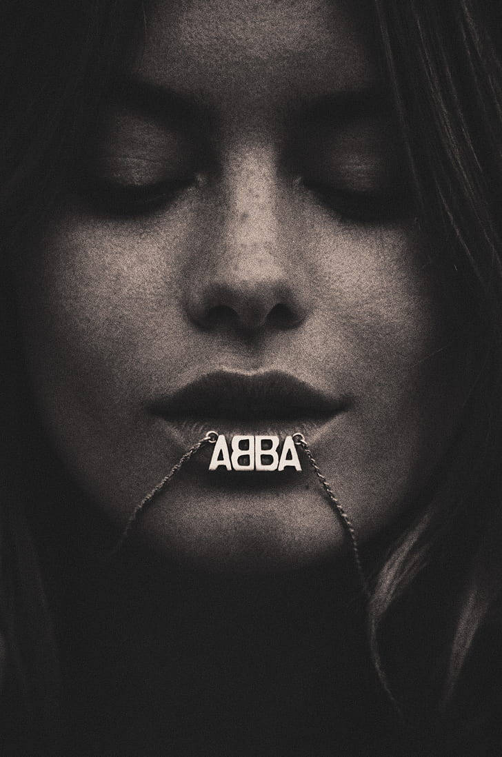 閉上眼睛的女性特寫肖像，戴著帶有 ABBA 文字的鏈條。