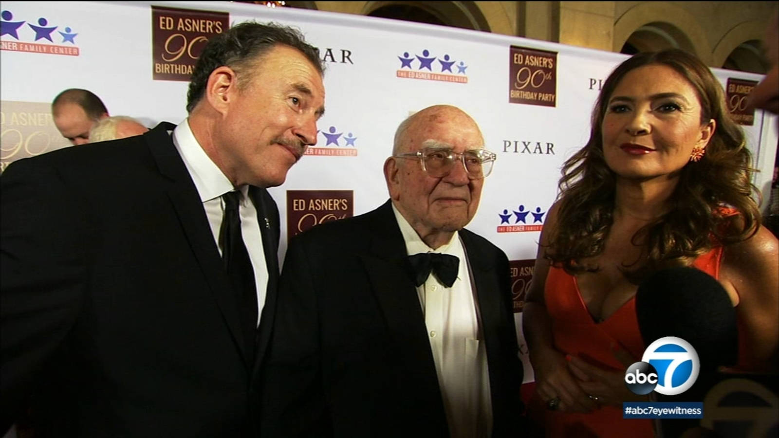 愛德華·阿斯納出席ABC紅毯活動 壁紙 — 三位衣著正式的名人喺 Ed Asner 嘅 90 歲生日派對上，喺一個有品牌標誌嘅紅地毯上合照。