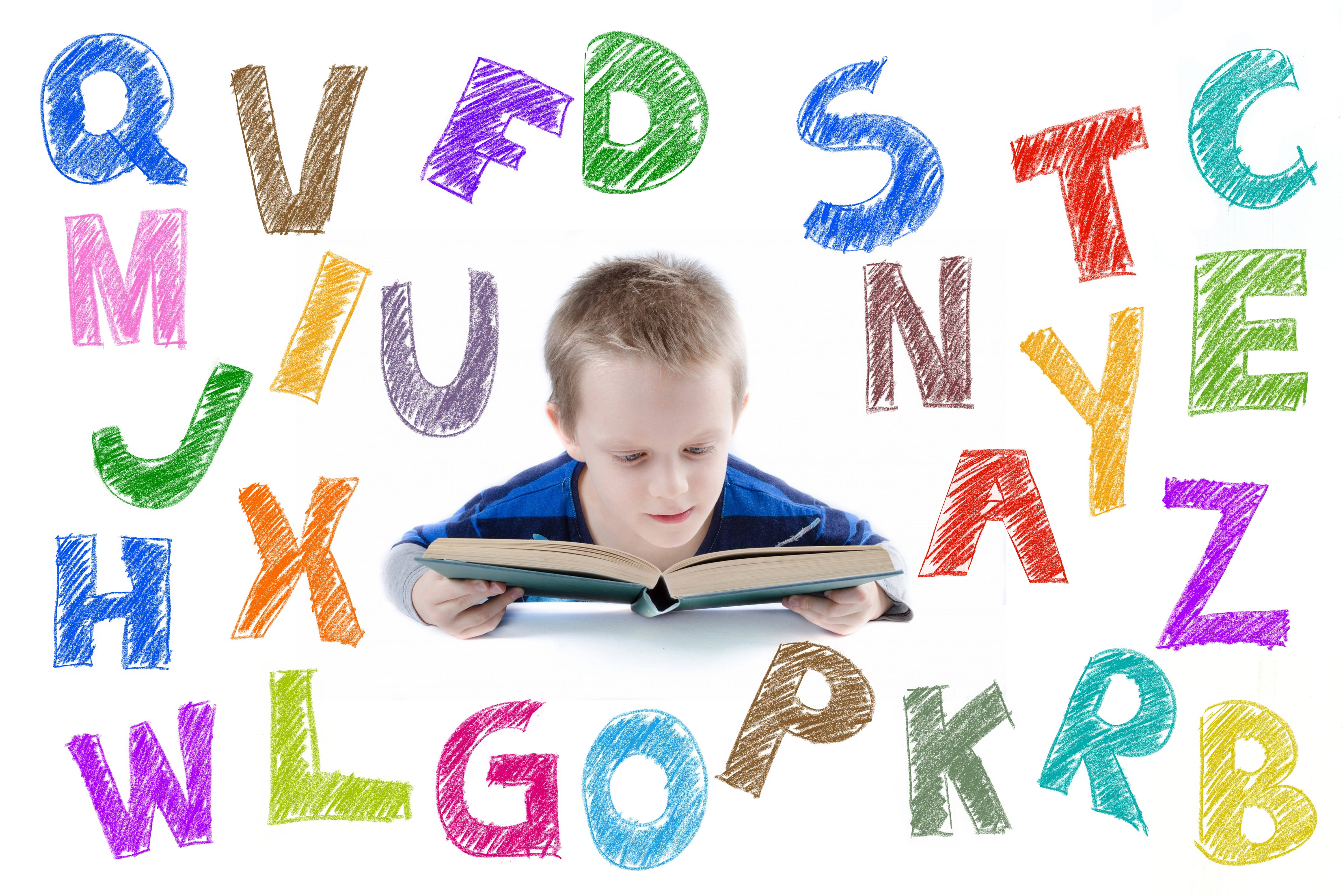 ABC幼童與書本 壁紙 — 一個小男孩在白色背景上，被色彩繽紛的手繪字母包圍，專心閱讀一本書。