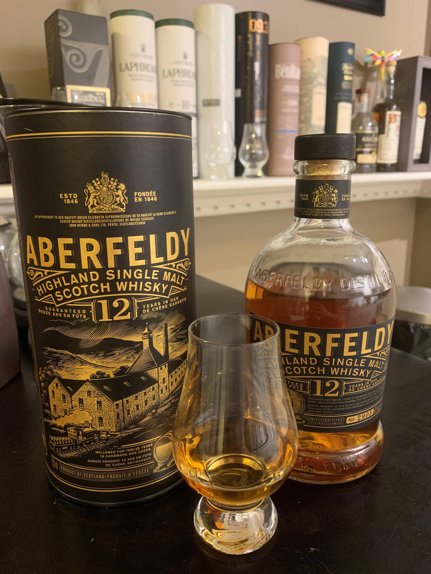 Aberfeldy 12年威士忌酒瓶和品酒杯在深色桌子上，帶有品牌包裝。