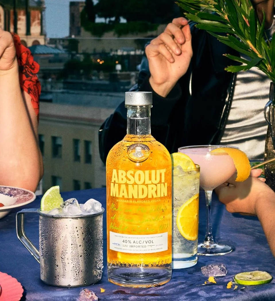 屋頂雞尾酒派對，包含 Absolut Mandrin 酒瓶和飲品，放在藍色桌布上。