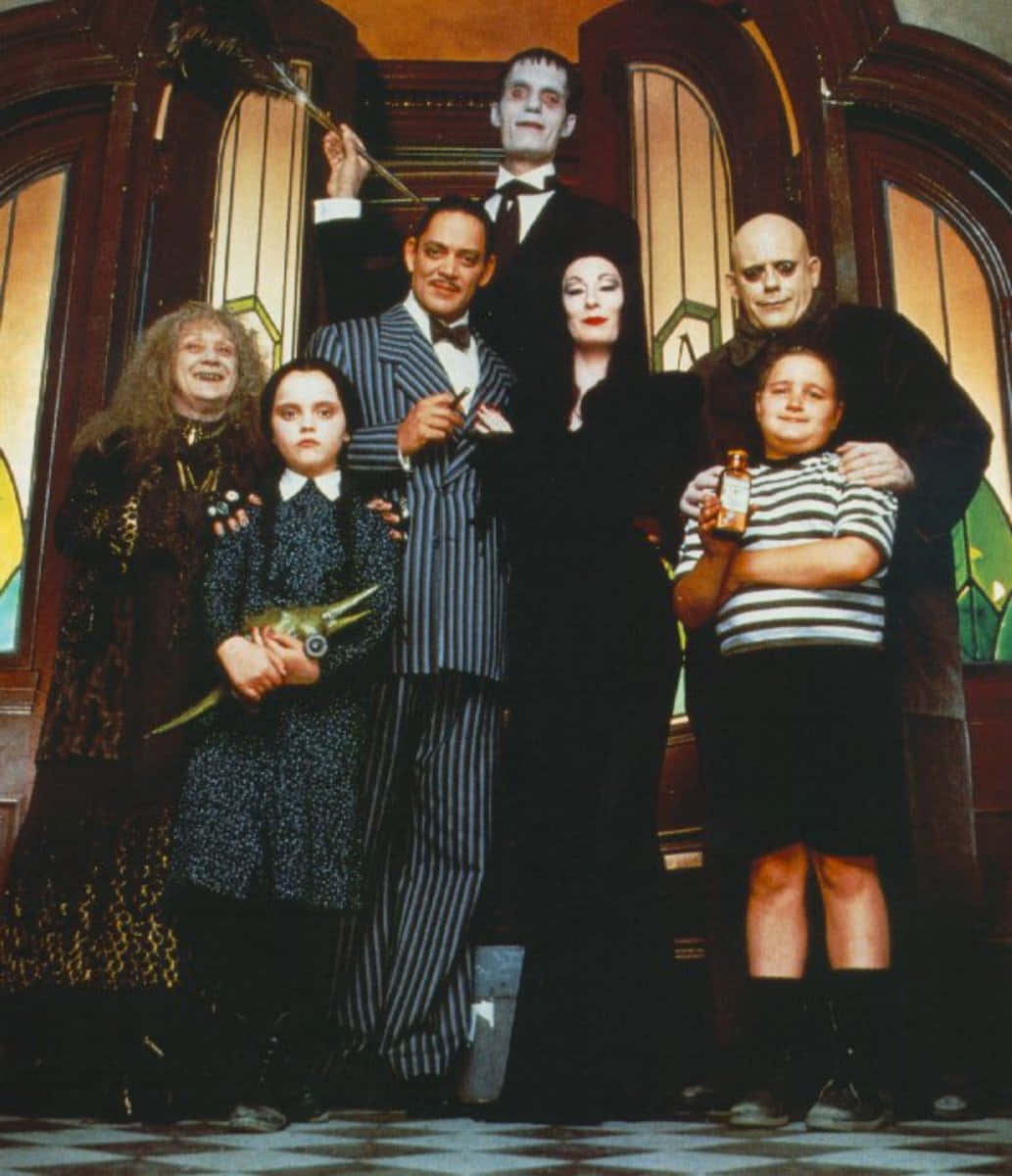 Addams家族合照 壁紙 — 阿達一族在他們擁有彩繪玻璃窗和棋盤地板的哥德式大宅中一起擺姿勢。