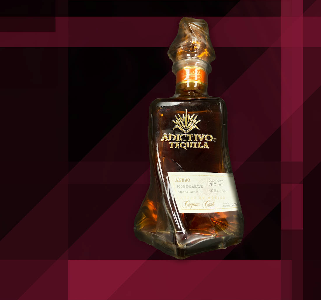 Adictivo 黑色超級陳年龍舌蘭酒 壁紙 — 時尚的Adictivo Tequila Añejo酒瓶在搶眼的幾何酒紅色和黑色背景上閃耀著琥珀色液體。