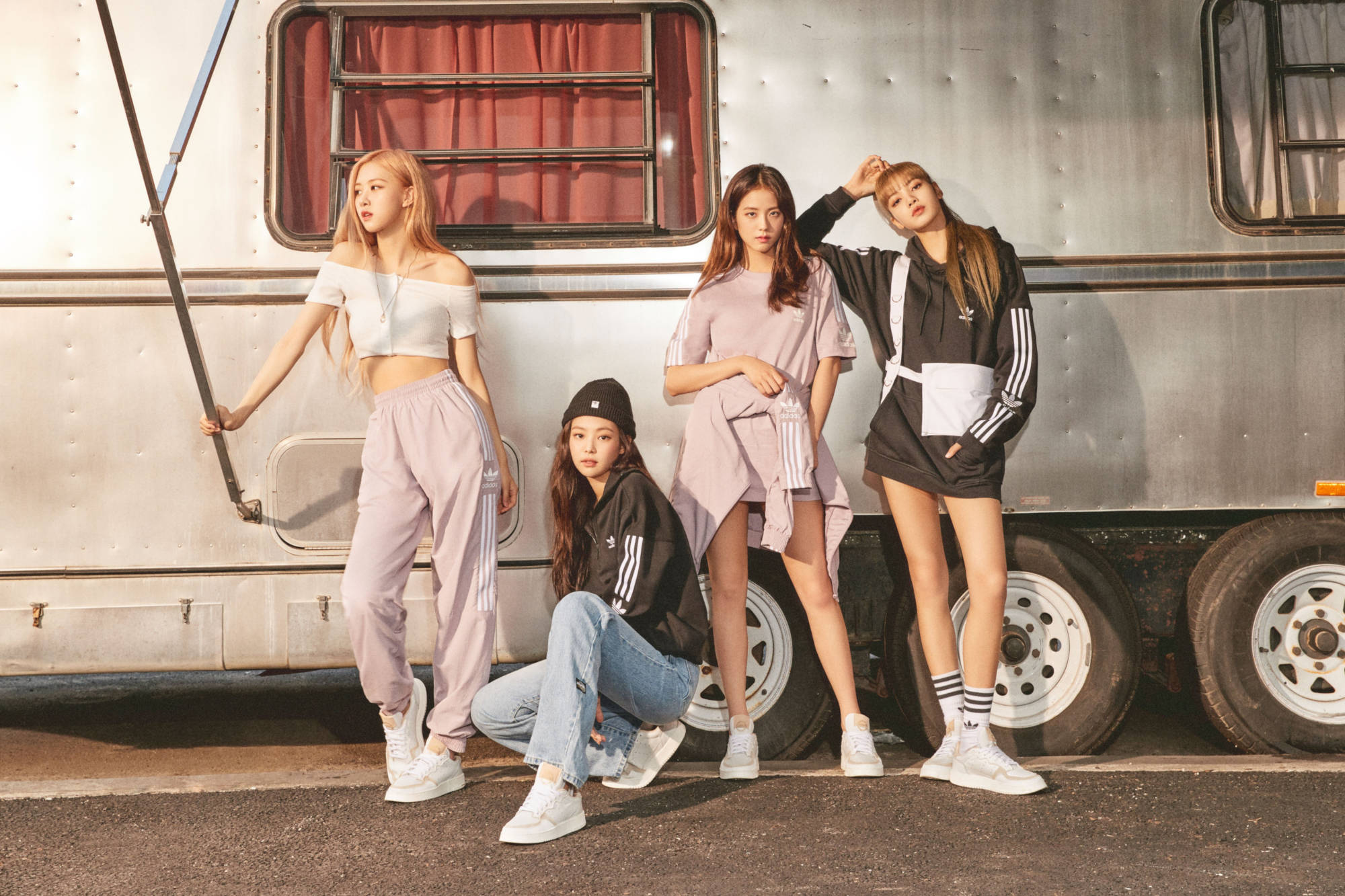 Adidas宣傳片黑pink桌面壁紙 壁紙 — 四位時尚年輕女性穿著運動服，自信地在帶有紅色窗簾的復古銀色露營車前擺姿勢。