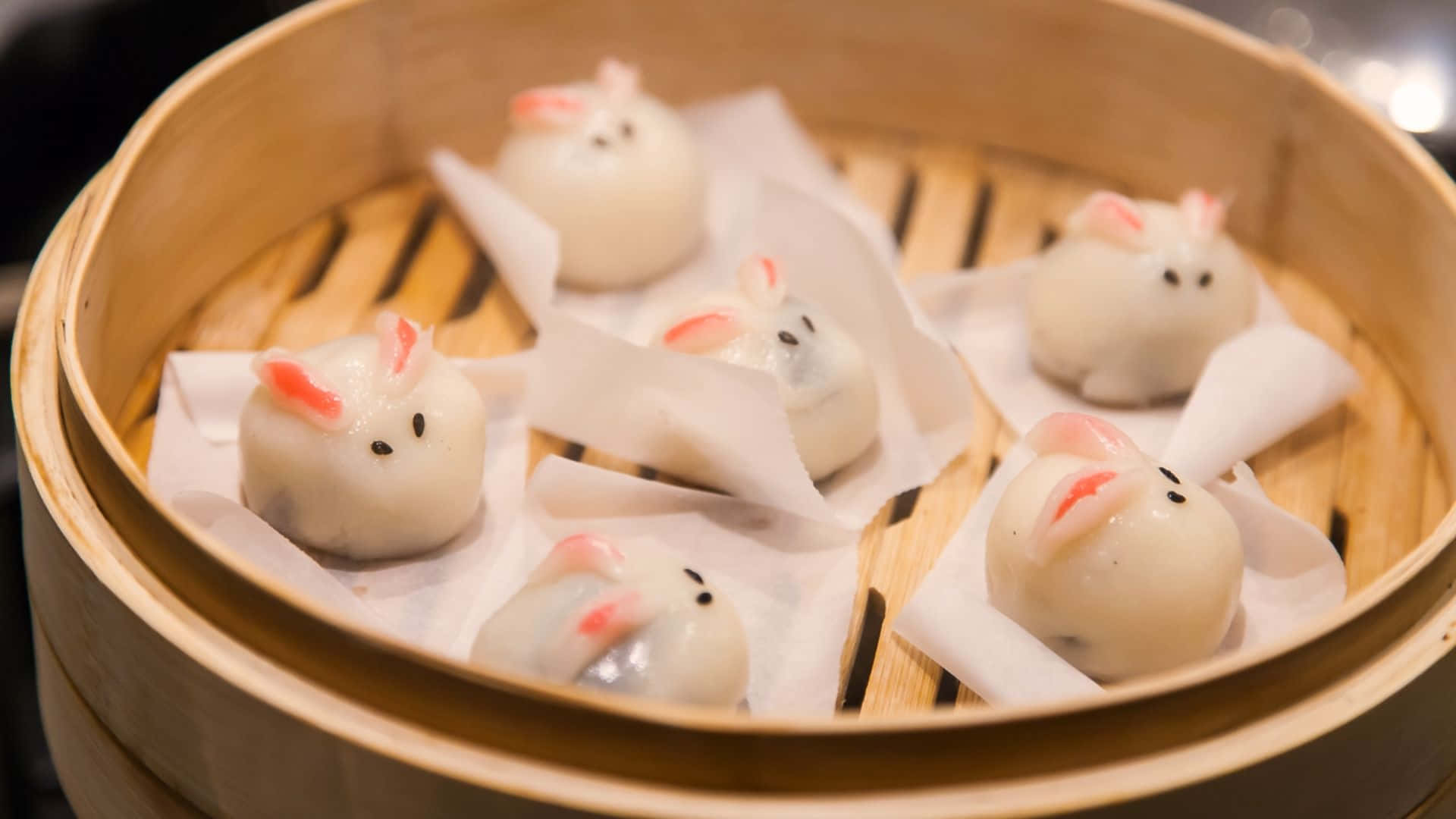  壁紙 — 可愛的兔子形餃子在鋪有烘焙紙的木竹蒸籠中輕輕蒸煮。