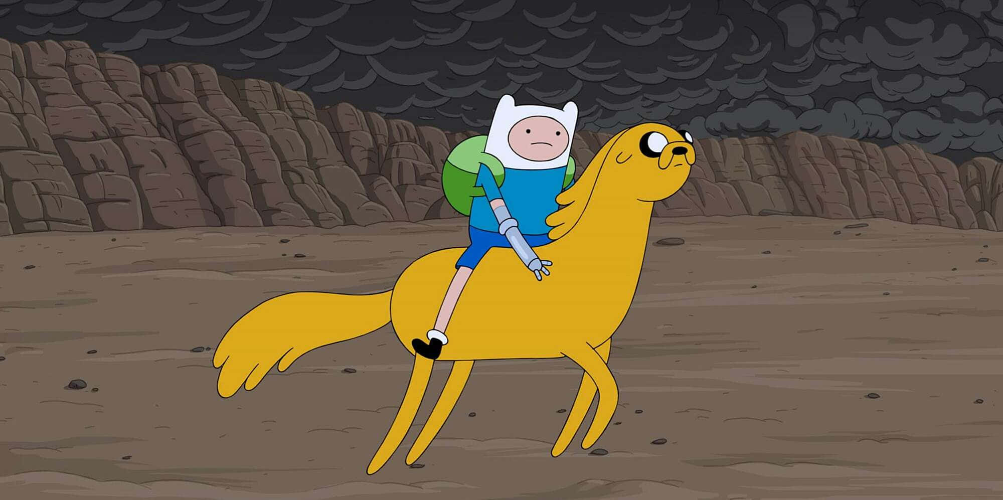 《Adventure Time》芬恩騎在傑克背上圖像 壁紙 — 一個卡通男孩騎著一隻黃狗穿過荒蕪的岩石景觀，天空灰暗風暴。