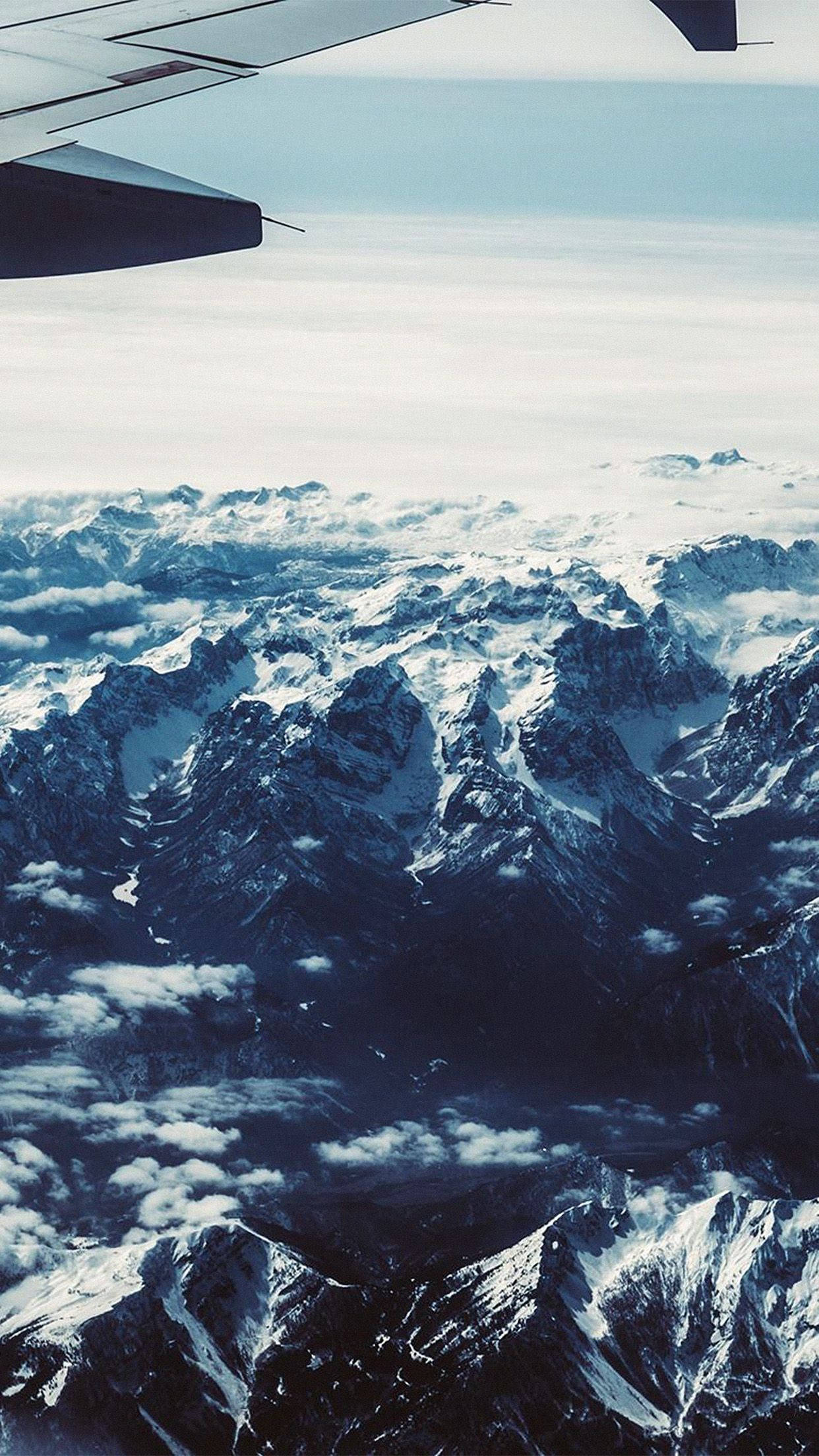 從飛機窗戶看到雲層上方積雪的山峰。
