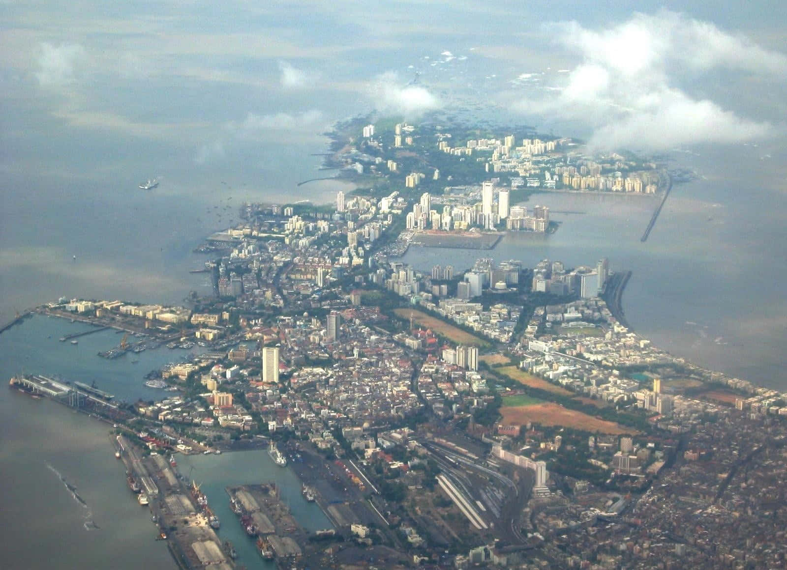 多雲天空下，沿海城市港口和密集建築物的鳥瞰圖。
