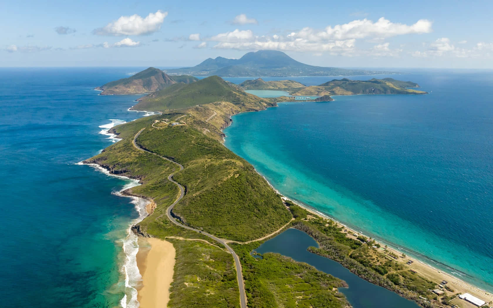  壁紙 — 鳥瞰一片翠綠島鏈，蜿蜒道路、沙灘與碧綠海水在明亮藍天下展現。