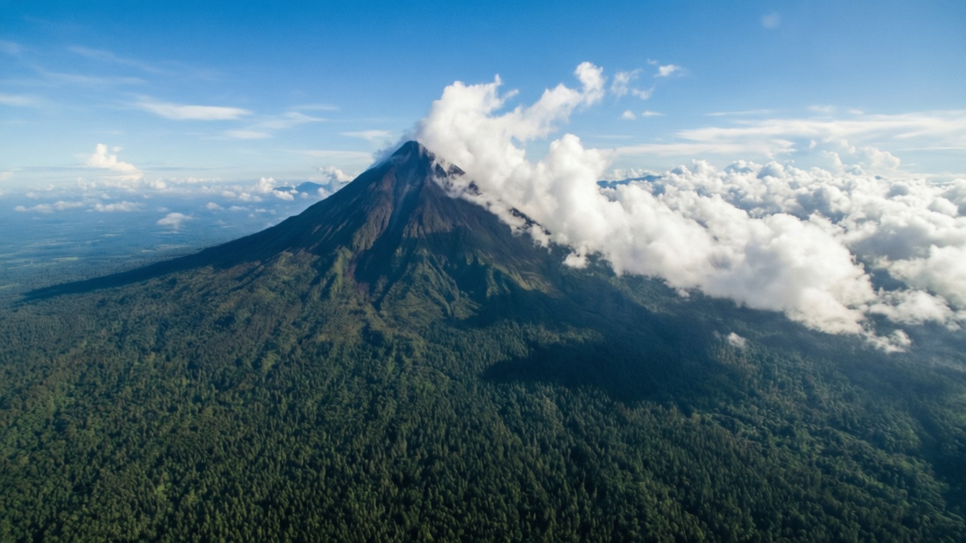 火山被綠色森林覆蓋，雲霧繚繞其山頂。