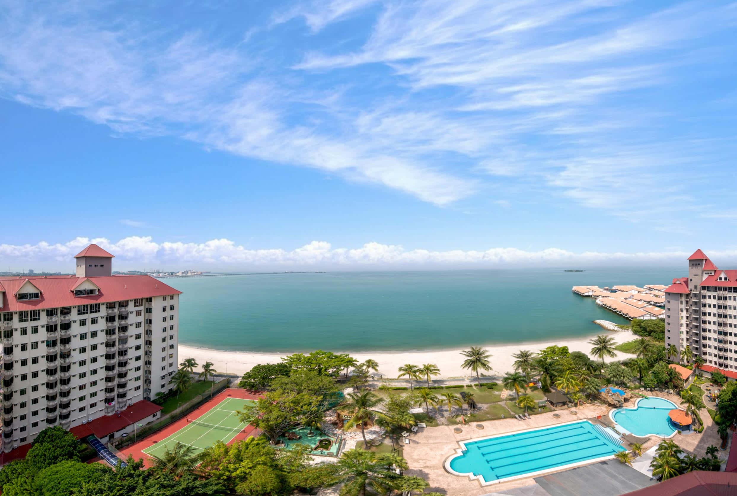 Beach Resort 桌布 壁紙 — 從高空俯瞰豪華度假村，擁有碧綠色的泳池、網球場和棕櫚樹，俯瞰著原始海灘和寧靜的海洋，天空湛藍明亮。