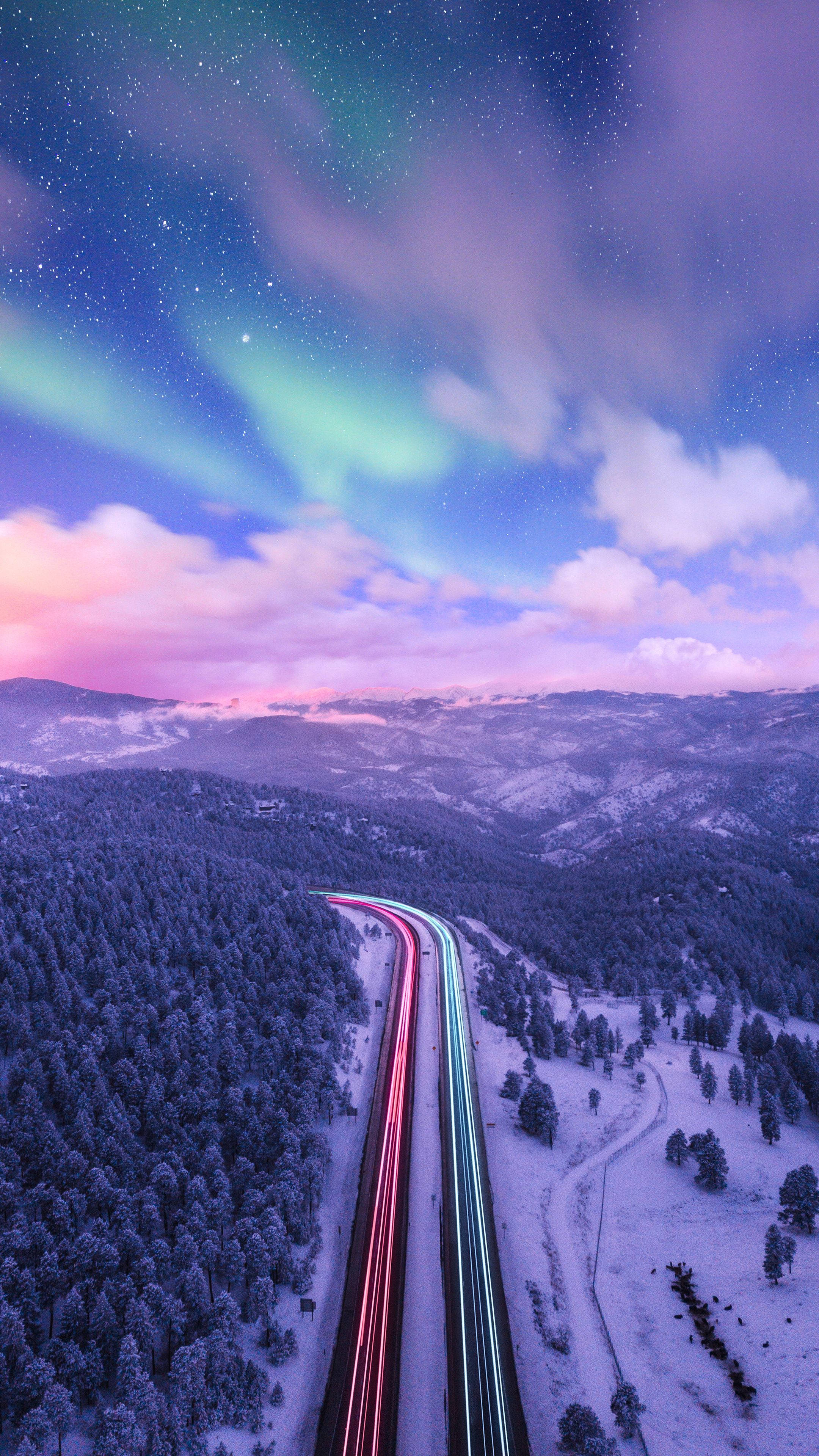 google 桌布 壁紙 — 黃昏時分，白雪覆蓋的山區高速公路的鳥瞰圖，充滿活力的北極光在上方舞動。