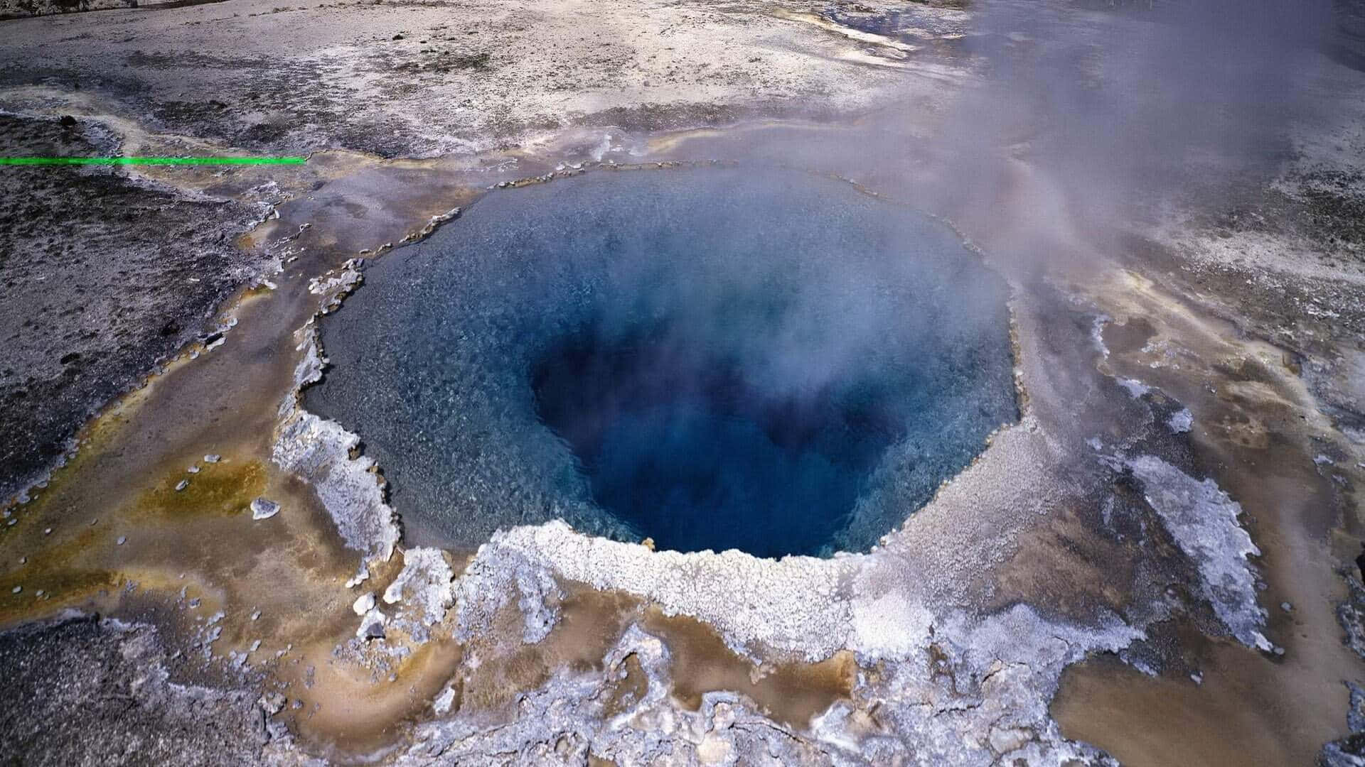  壁紙 — 俯瞰一個冒著蒸氣的地熱池，池水呈深藍色，周圍是富含礦物質的土地和蒸氣。