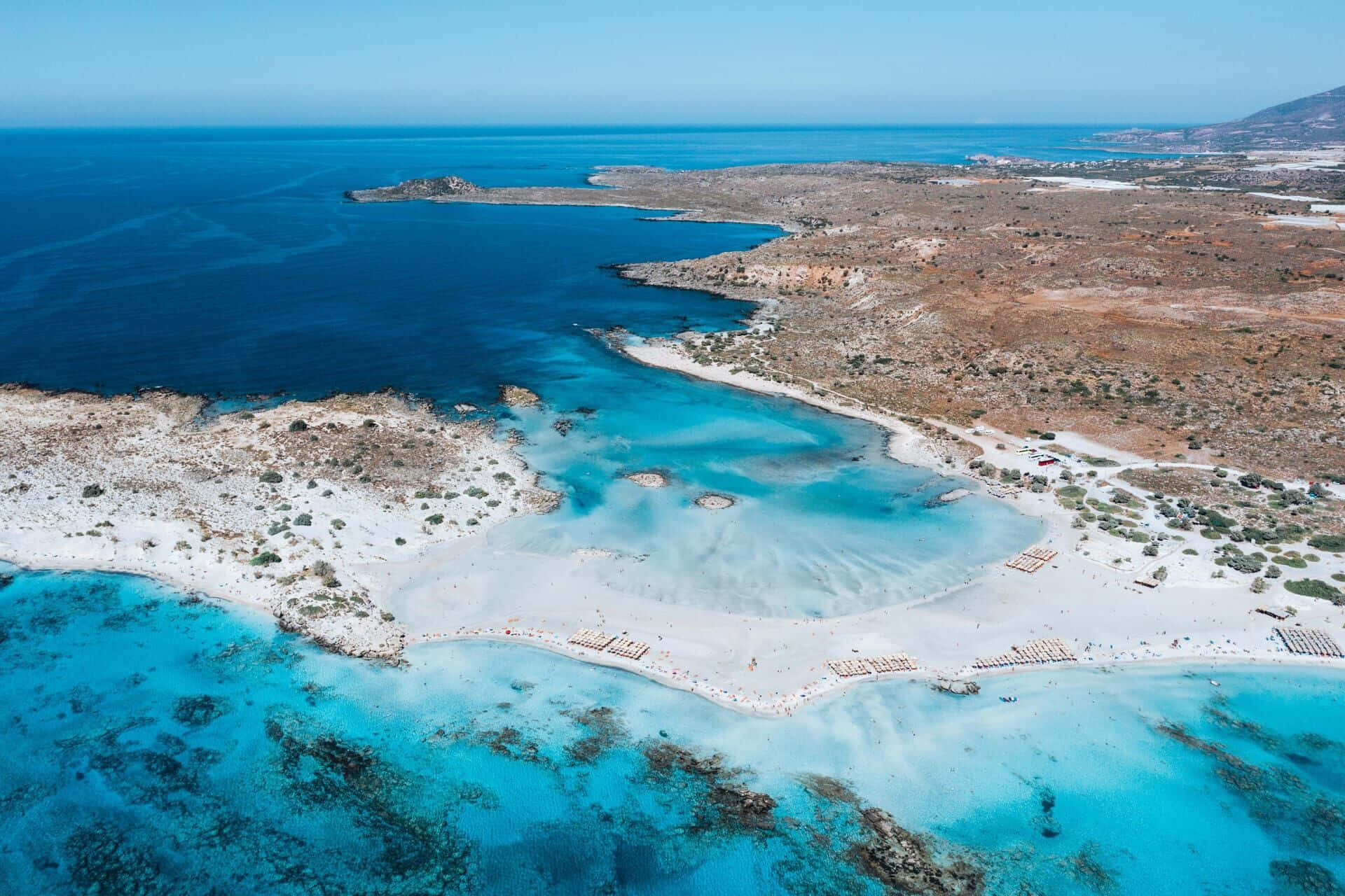 Greek Beach 桌布 壁紙 — 在清澈藍天下，白色沙灘與崎嶇懸崖之間令人驚嘆的碧綠潟湖的鳥瞰圖。