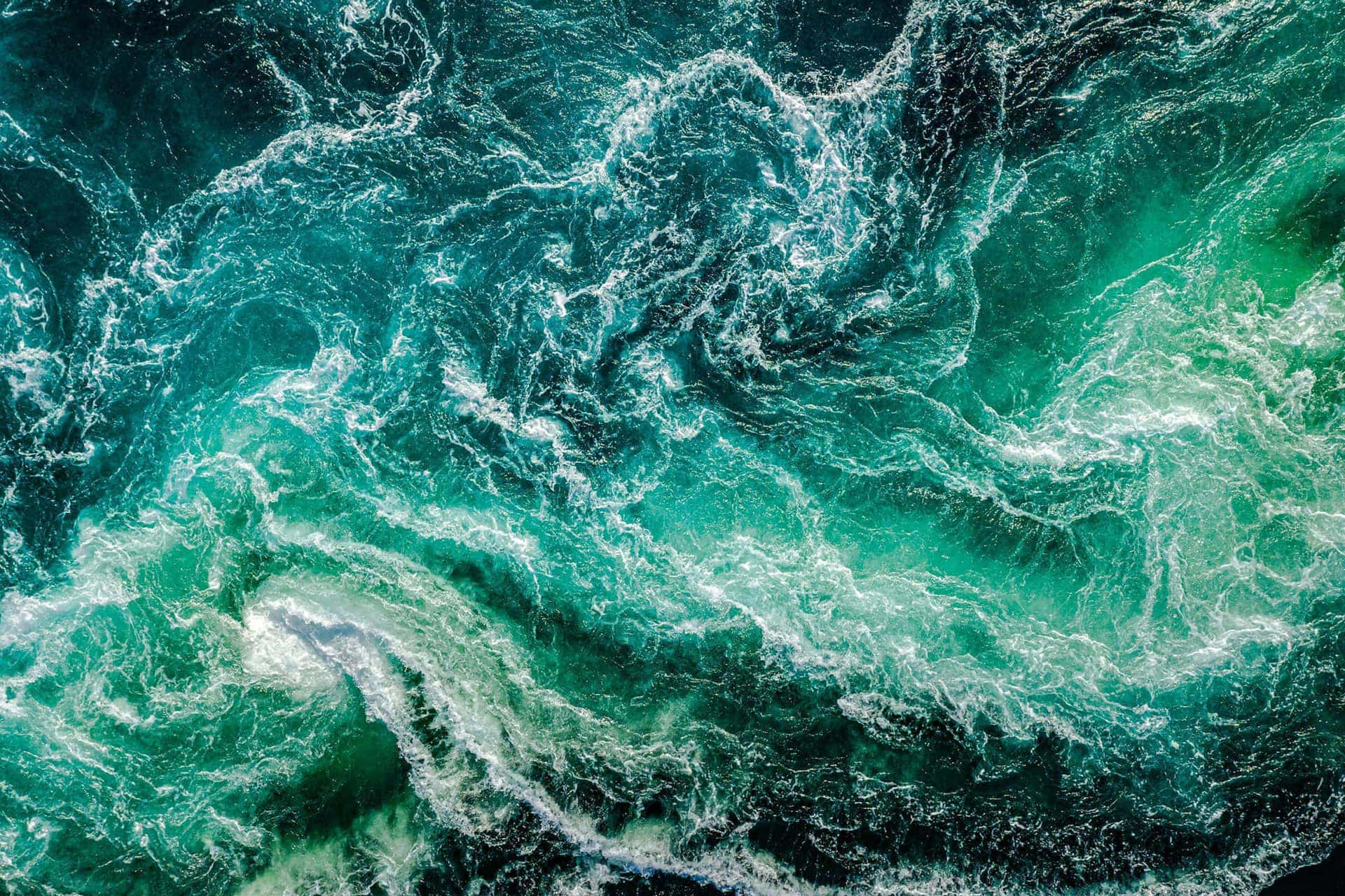  壁紙 — 從高空俯瞰，碧綠色的海洋波濤洶湧，白色泡沫形成複雜的漩渦圖案。